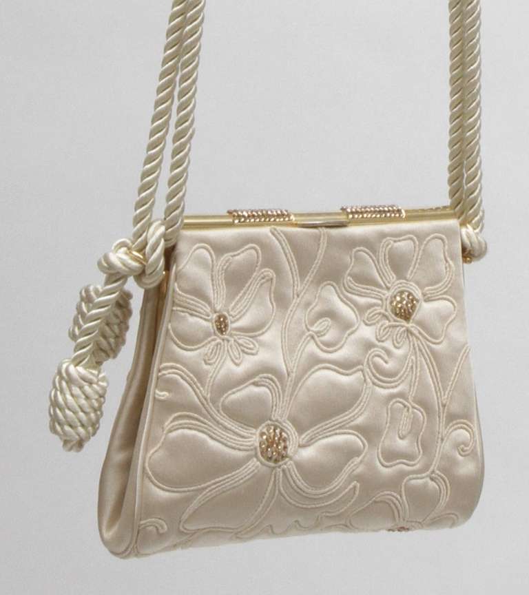 Beautiful champagne silk satin purse embroidered with silk rope embroidery and gold crystals. Silk satin rope cord with original mirror and coin purse included. Gold tone hardware accents. Kept is pristine condition.