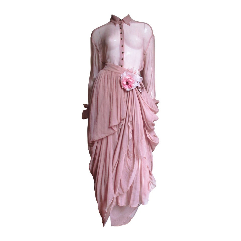 A gorgeous set from Dolce & Gabbana consisting of a shirt and skirt made of pale pink sheer silk .  The long sleeved top is shirt style with a small collar and ornate engraved, painted metal ball buttons up the front and 5 along each wide fold back