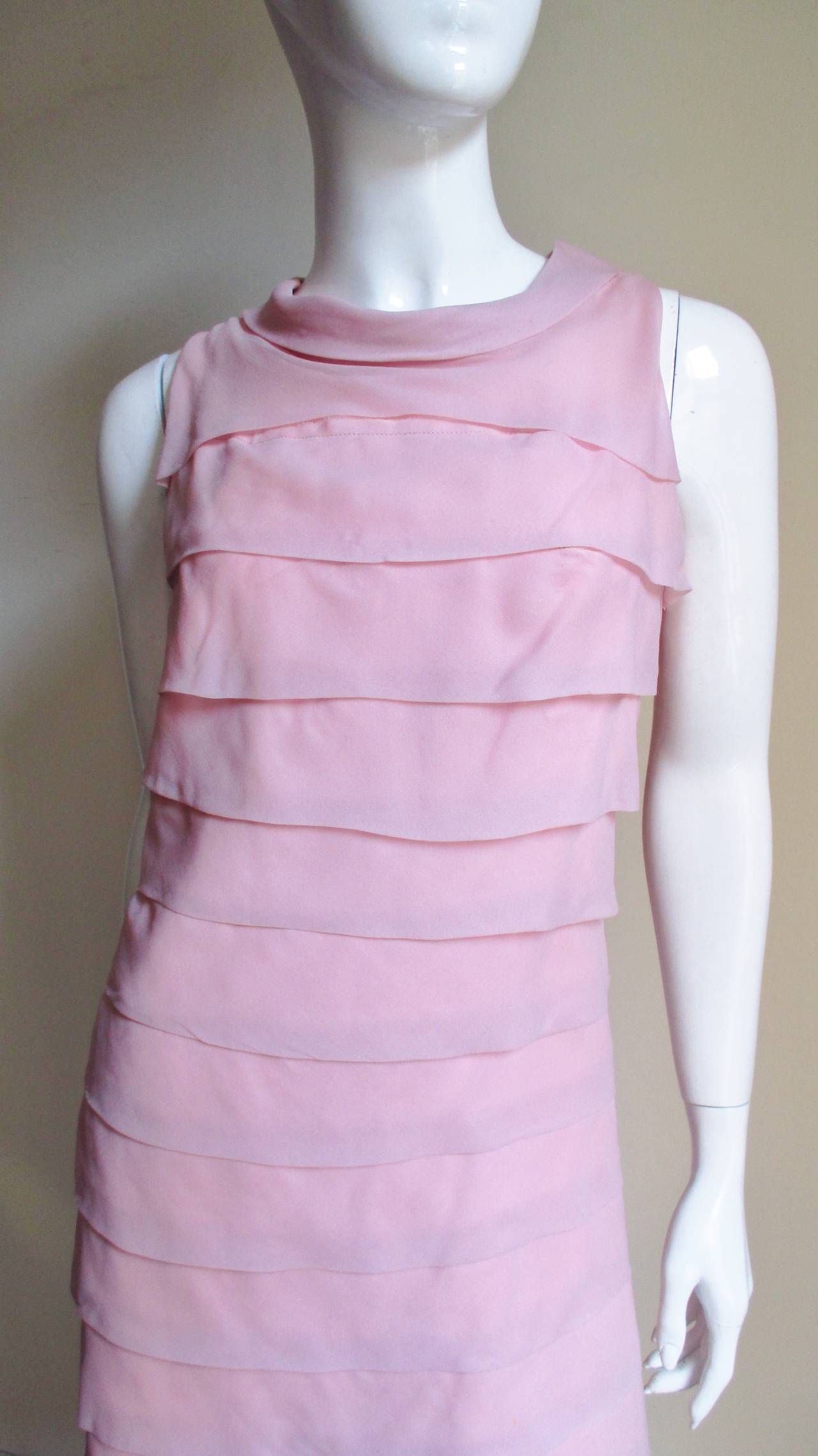 A pretty pink dress from Miss Elliette.  It is a sleeveless slightly A line dress with a rolled collar and horizontal rows of overlapping folds around it's circumference the entire length of the dress. It is fully lined with a back zipper.
Fits