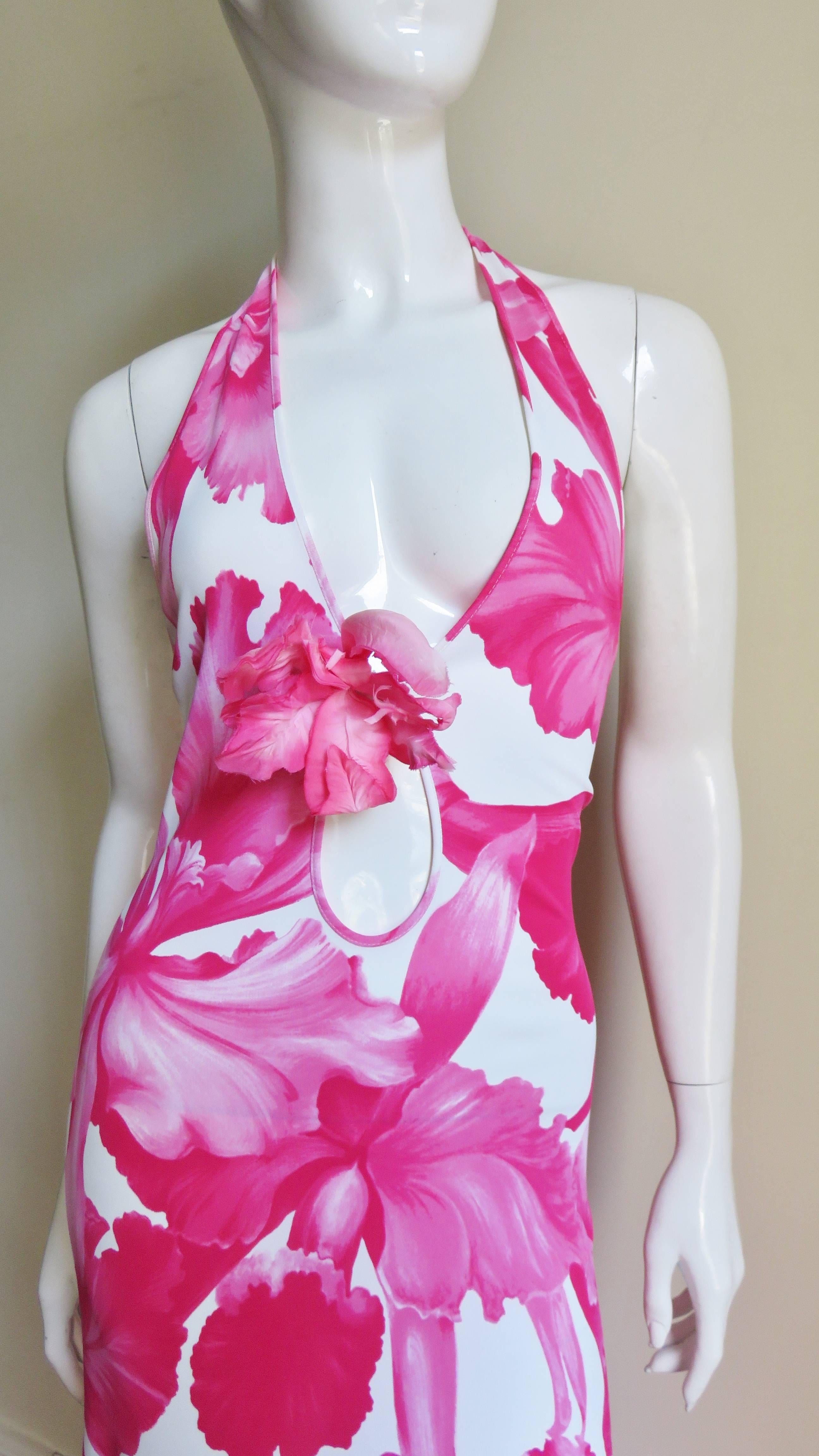 A fabulous jersey halter dress with large pink flowers on a white background.  The neckline is plunging with a matching removable silk flower pinned at the bottom then a keyhole is below that.  It is fitted through the hips and has an A line skirt. 