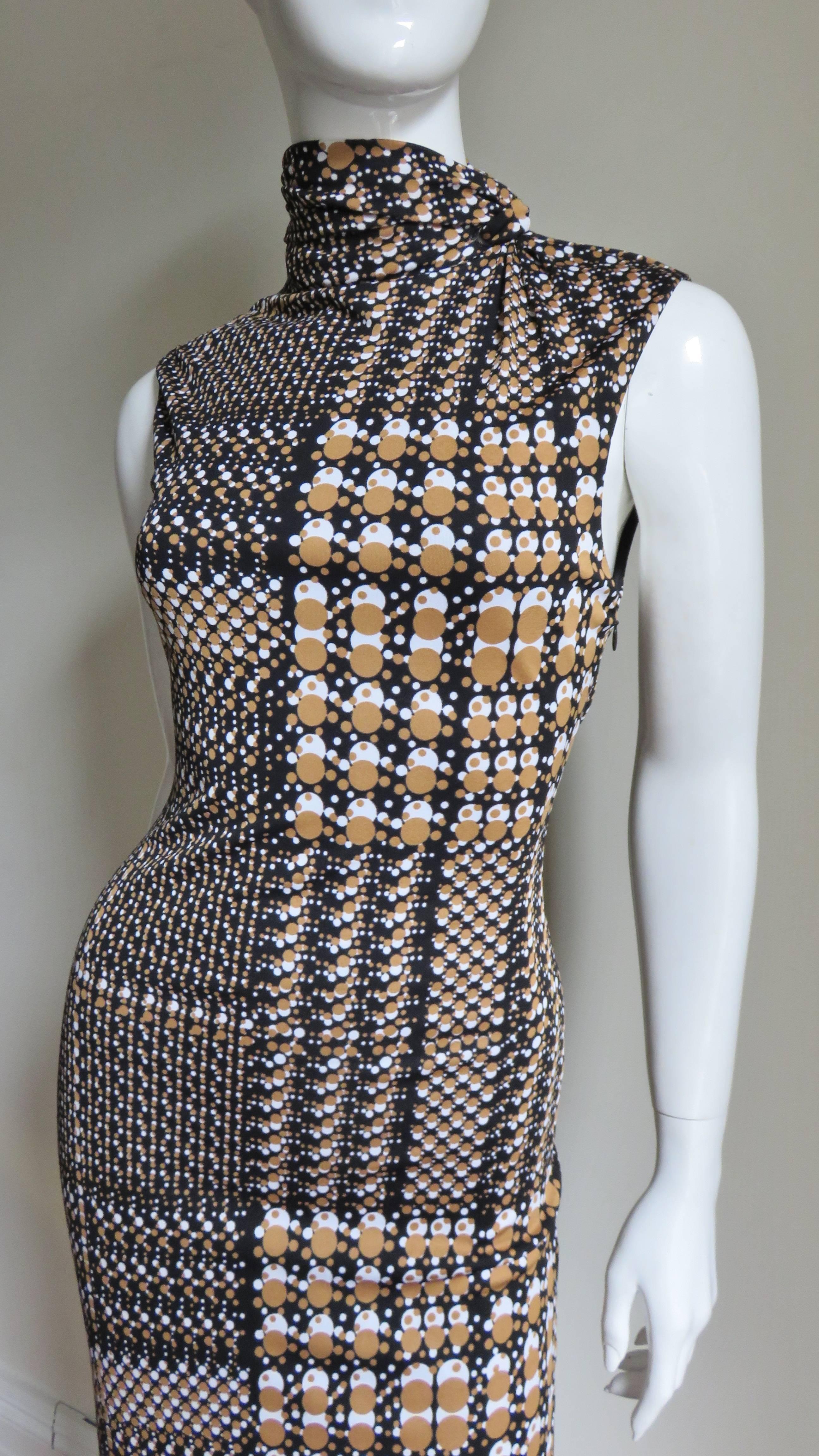 A fabulous stretch silk bodycon dress from Gianni Versace in tan and white abstract dots of varying sizes on a black background.  It is sleeveless with a ruched stand up collar which wraps and tucks with snap closures.  There is a slash detail