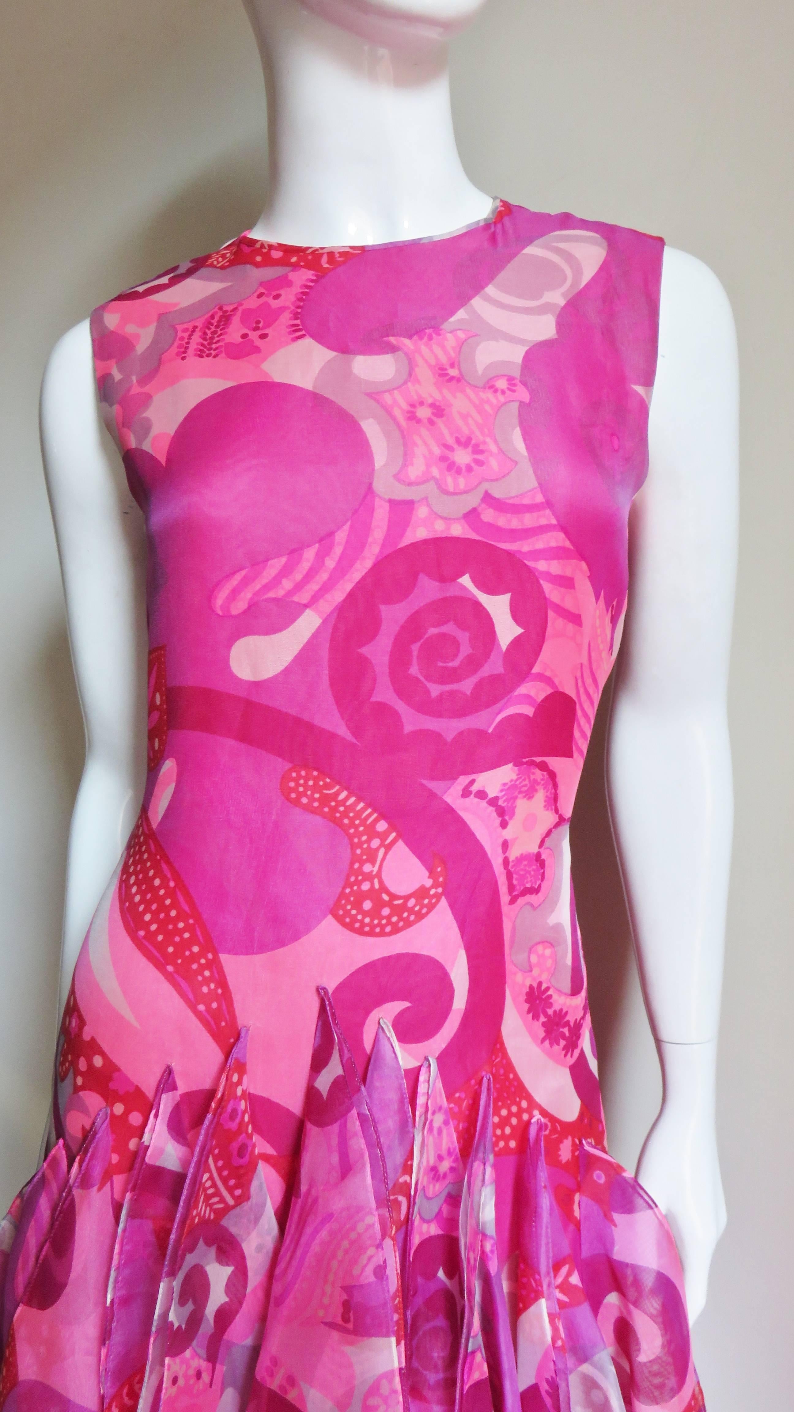 An extraordinary couture silk dress from Pierre Cardin in a brightly colored abstract print in varying shades of pink with red.  It is sleeveless with a simple neckline semi fitted gently following the body's curves to the hips.  There are dozens of