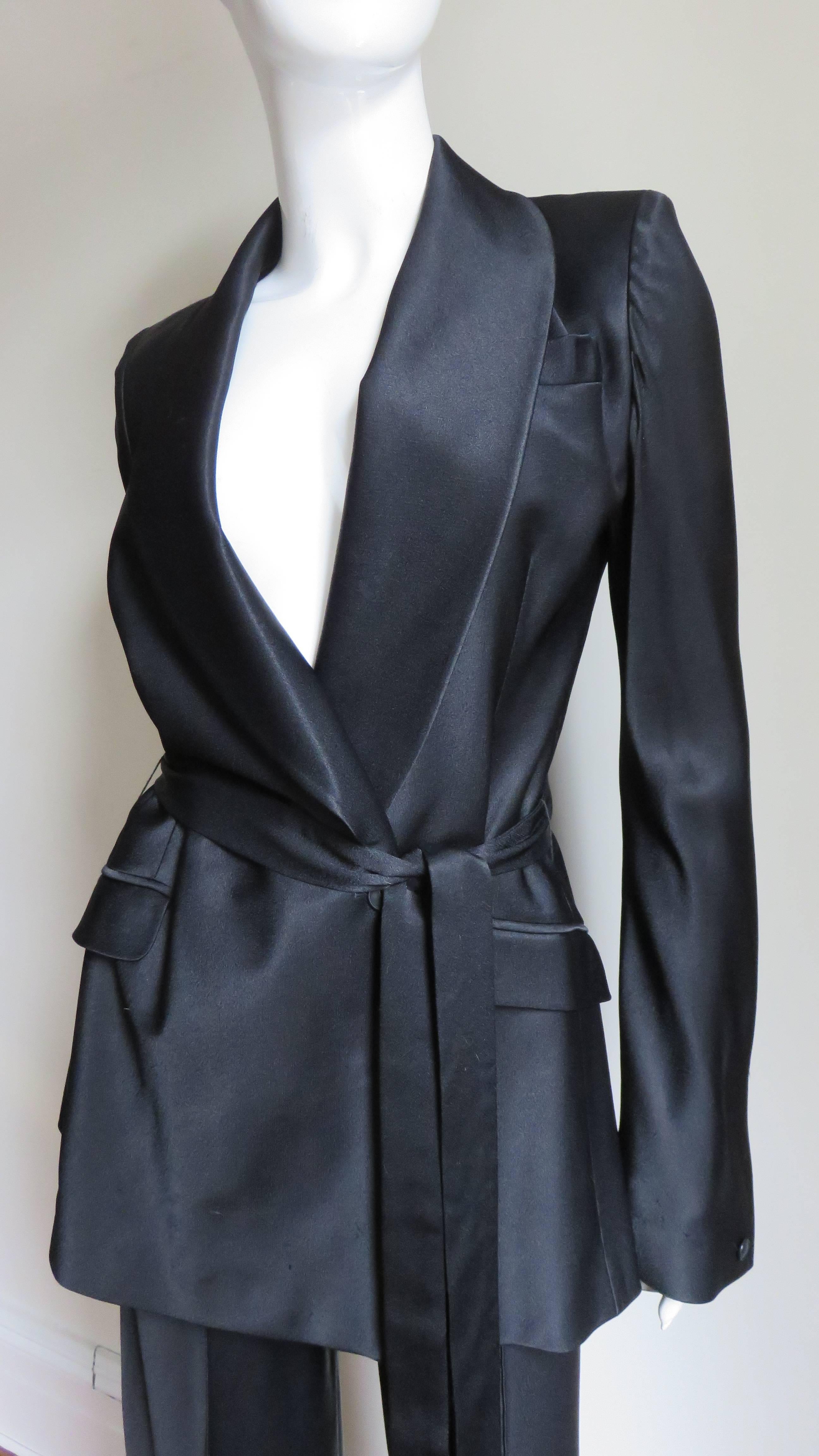 So fabulous...a black silk wrap jacket and full leg pants from John Galliano.  The jacket has a shawl collar, slanted hip flap pockets and long bell sleeves. It wraps and closes with an inner and outer button at the waist, comes with a matching tie