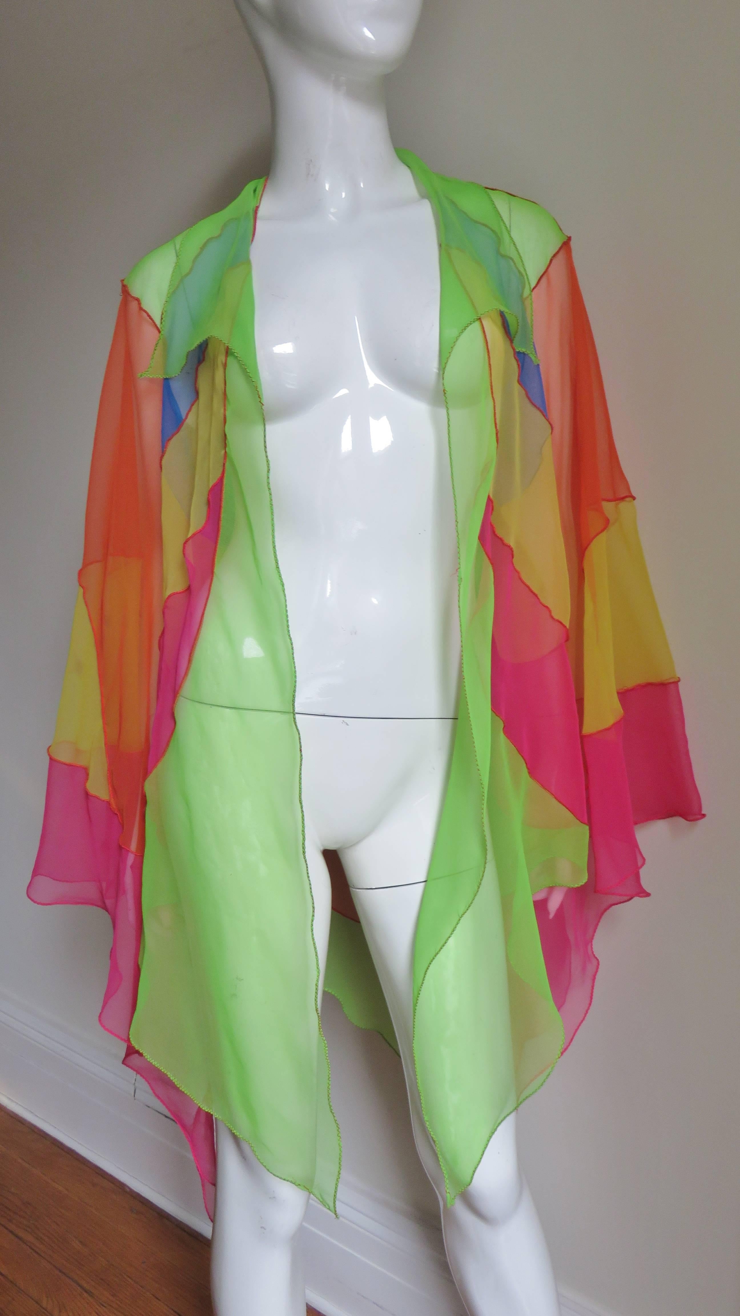 A gorgeous sheer silk color block stain glass effect patchwork of colorful shapes joined together with red stitching forming an open draped jacket from Stephen Burrows.  It has a long shirt collar, long full draping bell sleeves with points, and an