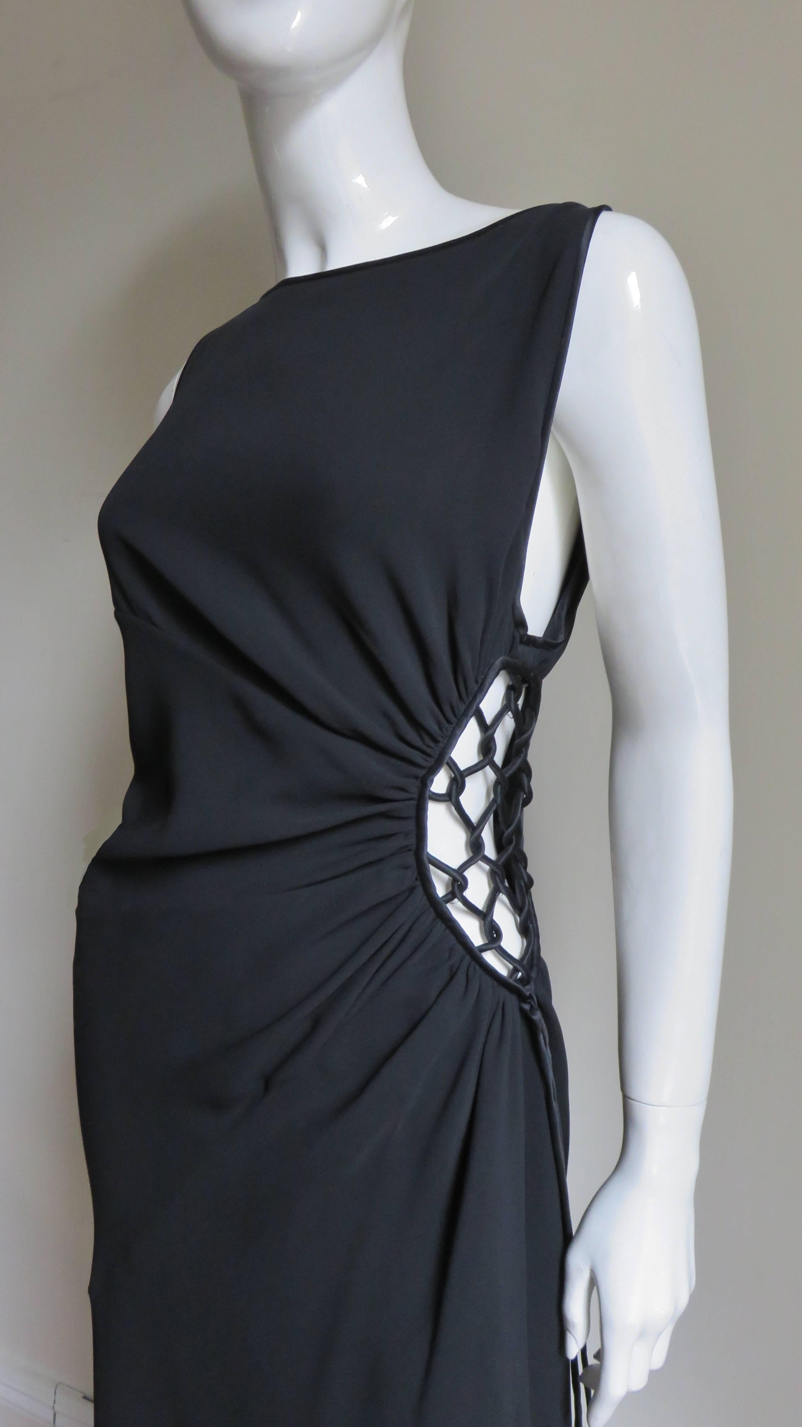 A fabulous black silk gown from Valentino.  It is sleeveless with a bateau neckline and a large oval cut out at one side with woven black silk piping over it.  There are seams in rays emanating from this cut out creating a slight ruched effect.  The