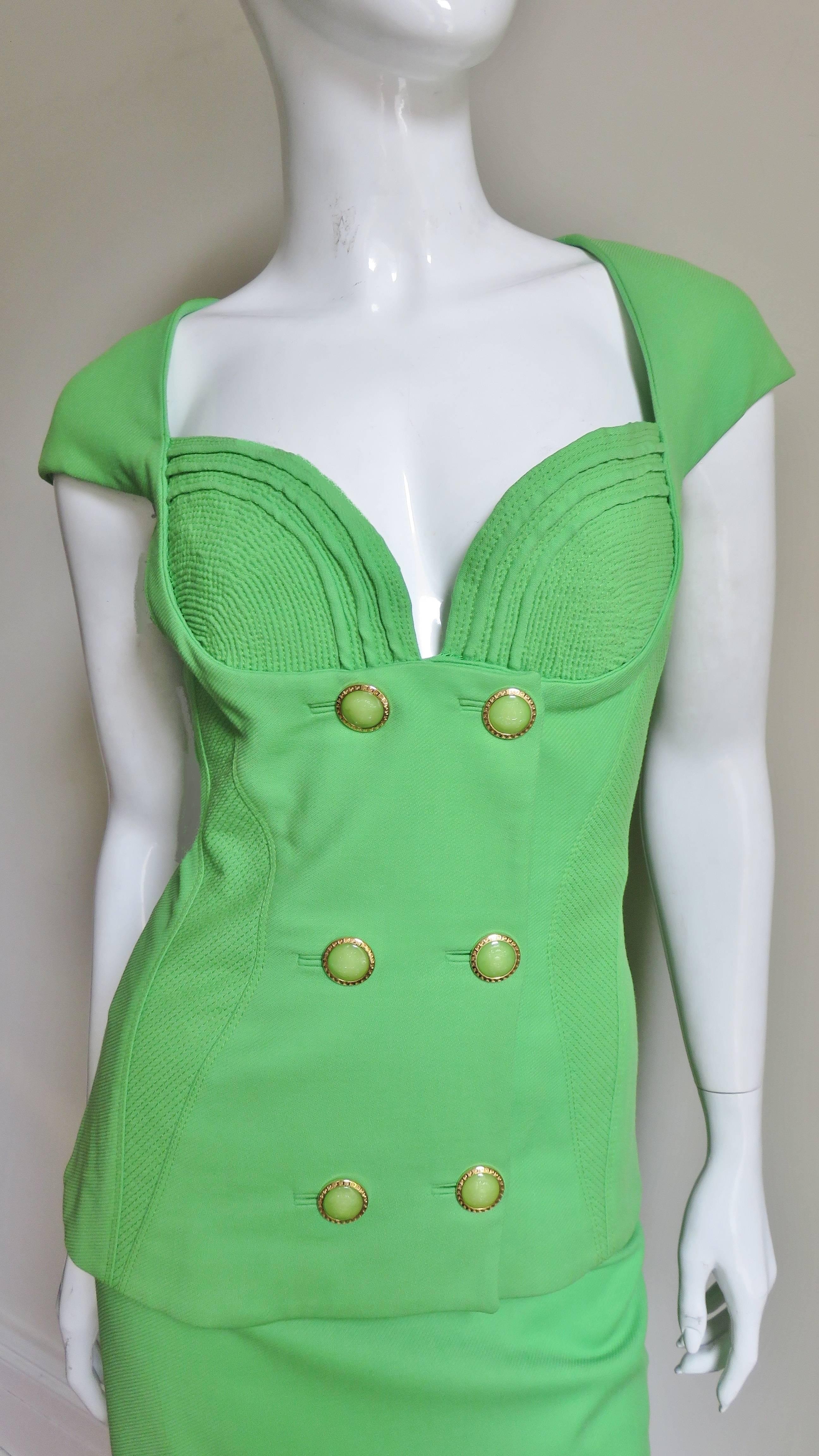 A spring green silk skirt and jacket set from Gianni Versace Couture. The double breasted jacket has elaborate rows of stitching detail around bust cups and at angles along curved panels on the sides nipping in the waistline. It has cap sleeves,