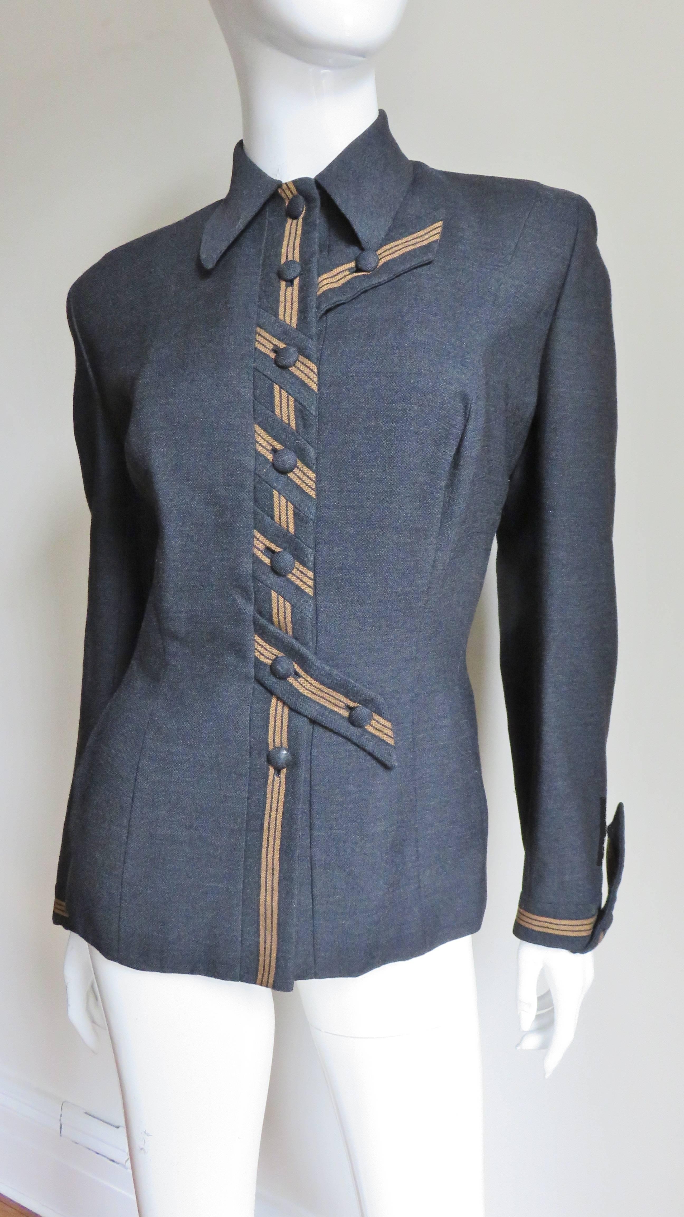 A stunning 1940's charcoal grey fine wool jacket by Sally Milgrim.  It has a shirt collar, princess seaming and shoulder padding.  The front closes with self covered buttons on a placket with tan striping.  The center 3 buttons are placed on angled