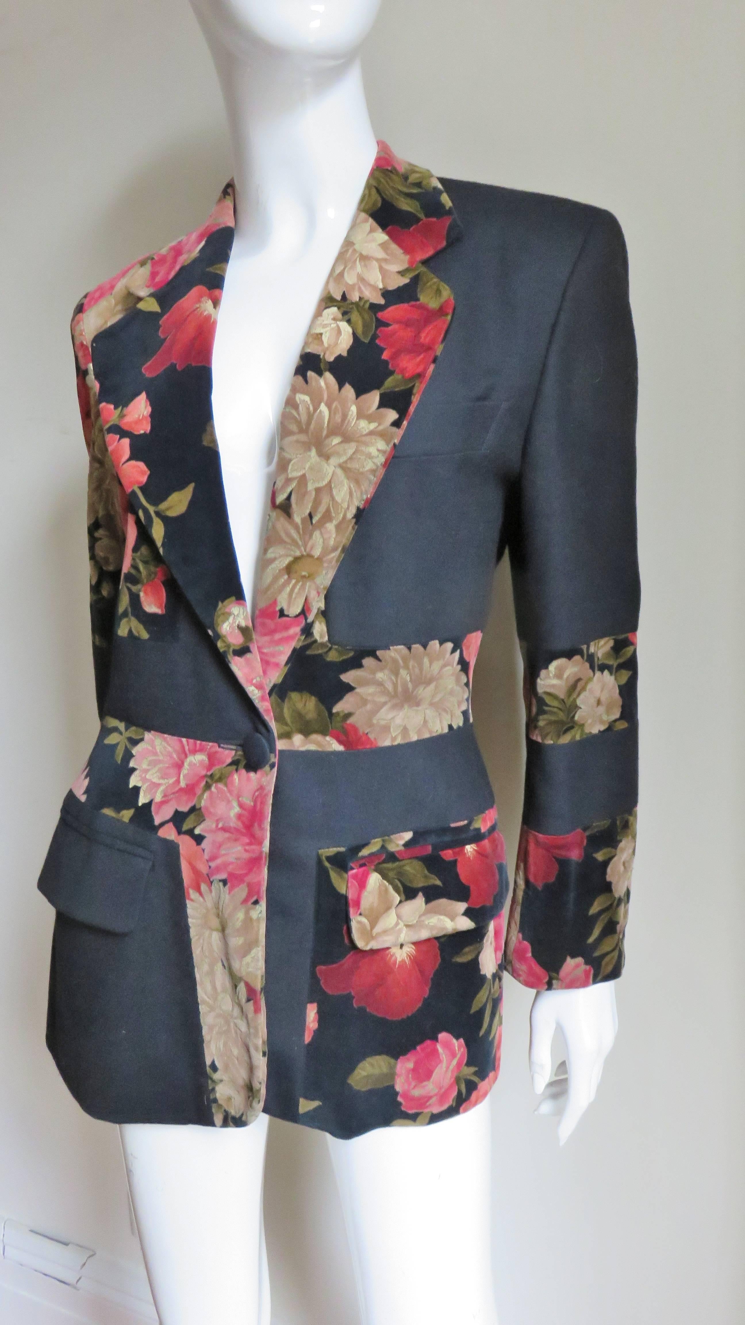 A fabulous jacket from Moschino Couture. It is a blazer style jacket with 2 front flap pockets, a breast pocket, a lapel collar and slight shoulder padding. It has an alternating fabrics-red and gold flowers on black velvet with solid black wool
