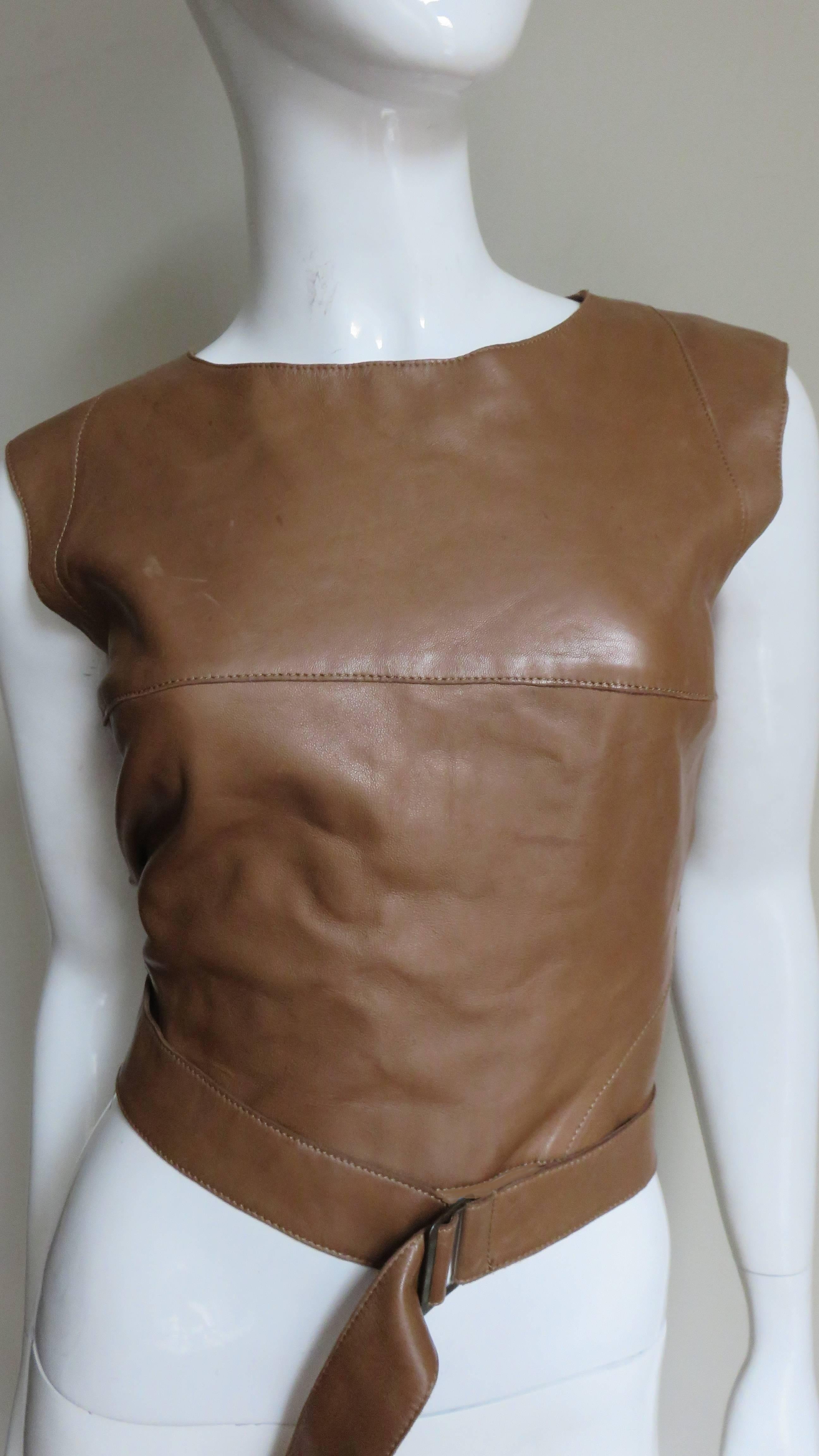 A great toffee colored leather top by Kenzo.  It has a crew neckline and inset triangangular panels around the upper armholes to extend the shoulders.  The back is cropped at the middle and there are 2 straps extending from the side waist wrapping