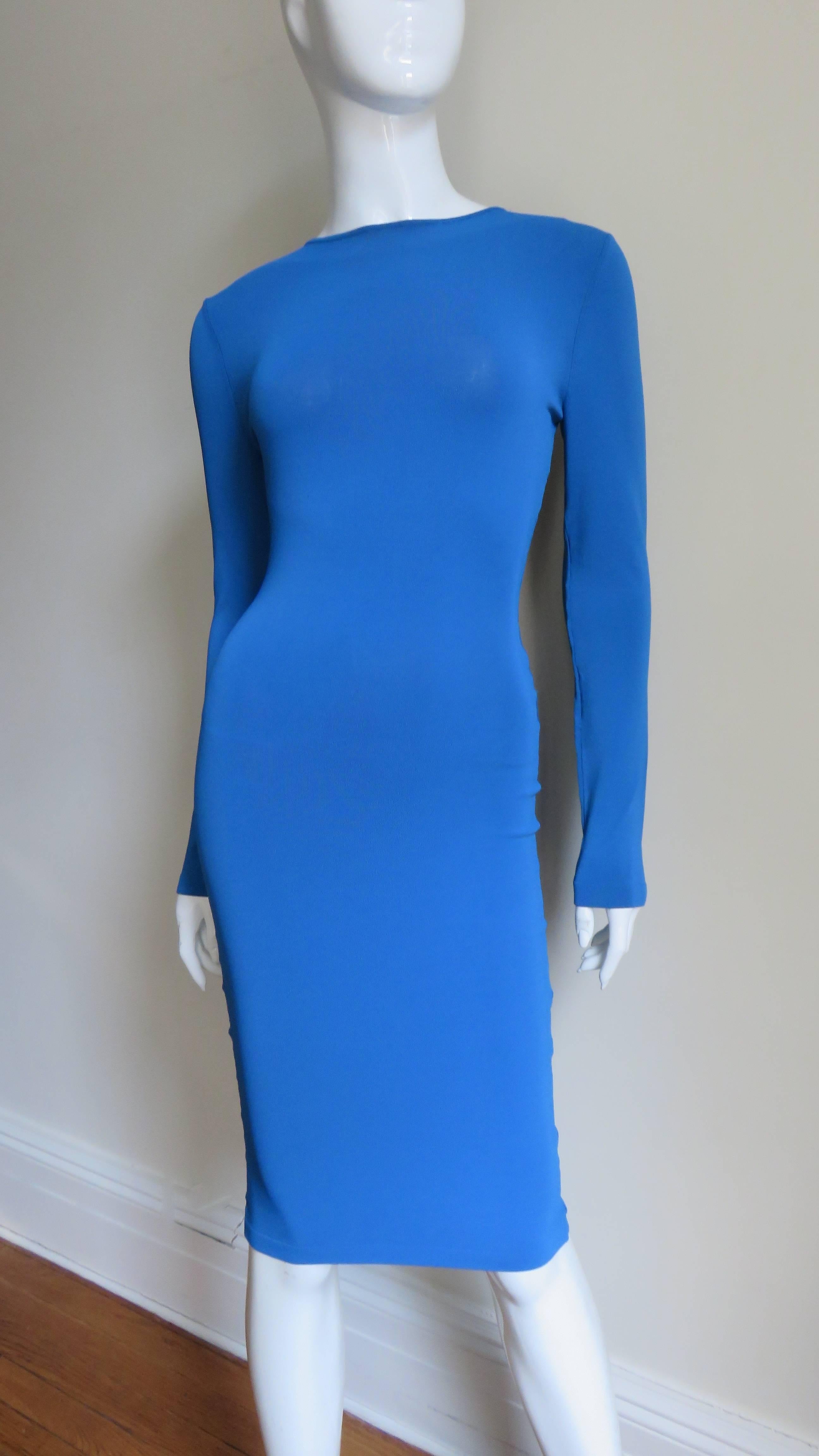 A fabulous bright turquoise blue jersey body conscious dress from Alexander McQueen. It is fitted with long sleeves and an amazing deep cutout back draped with fine silver chains it's length.  It is unlined with the exception of the mesh under the