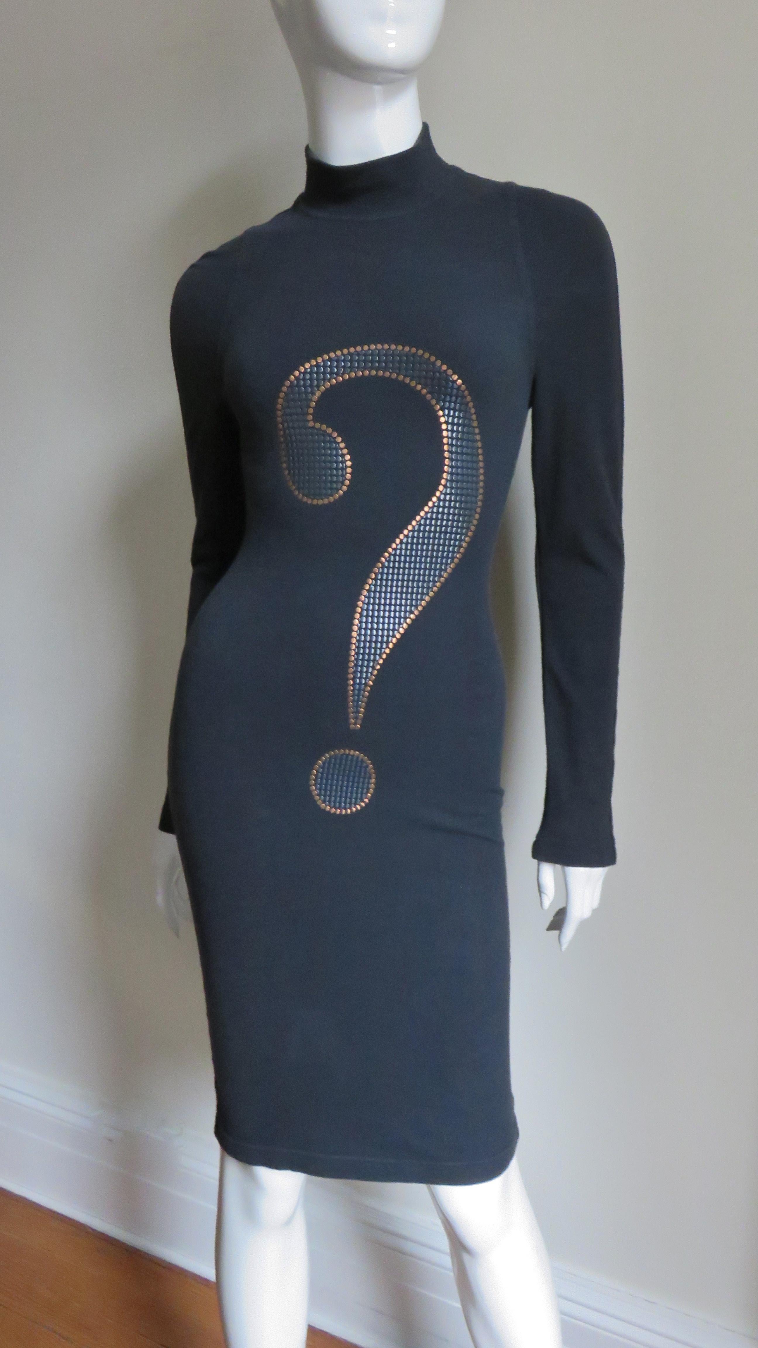 A black cotton jersey dress from Moschino.   It has a stand up collar, long sleeves and a large metallic applique question mark on the front.  It is unlined and slips on over the head.
Fits sizes Extra Small, Small, Medium.

Bust  33-36