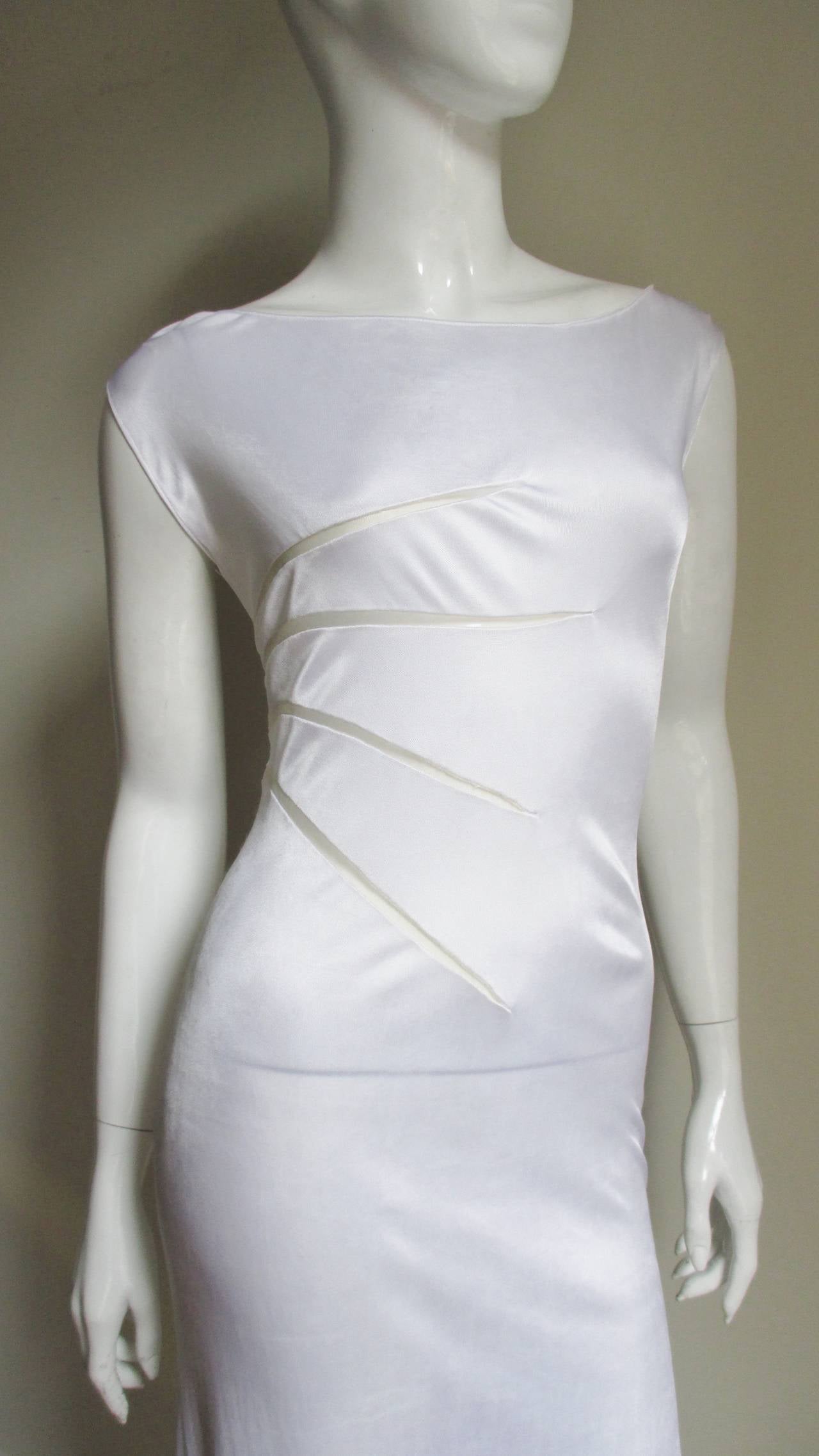 A beautiful simple white fine knit silk dress from Gianni Versace Couture.  It is fitted through the hips to a slight flare at the hem.  There are fabulous mesh cut-outs which reaching out in a fan of rays from the left side waist line, bust through