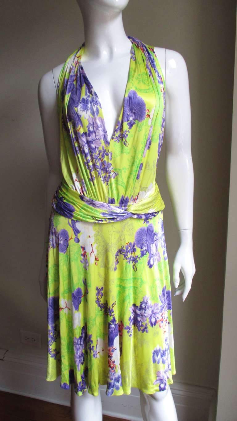 A gorgeous silk jersey plunge halter dress from Versace. Vibrant color combination in violet, white and orange flower pattern on a yellow background of flowers, cupids, early 1900's scenes with people and architecture intricately sketched in bright