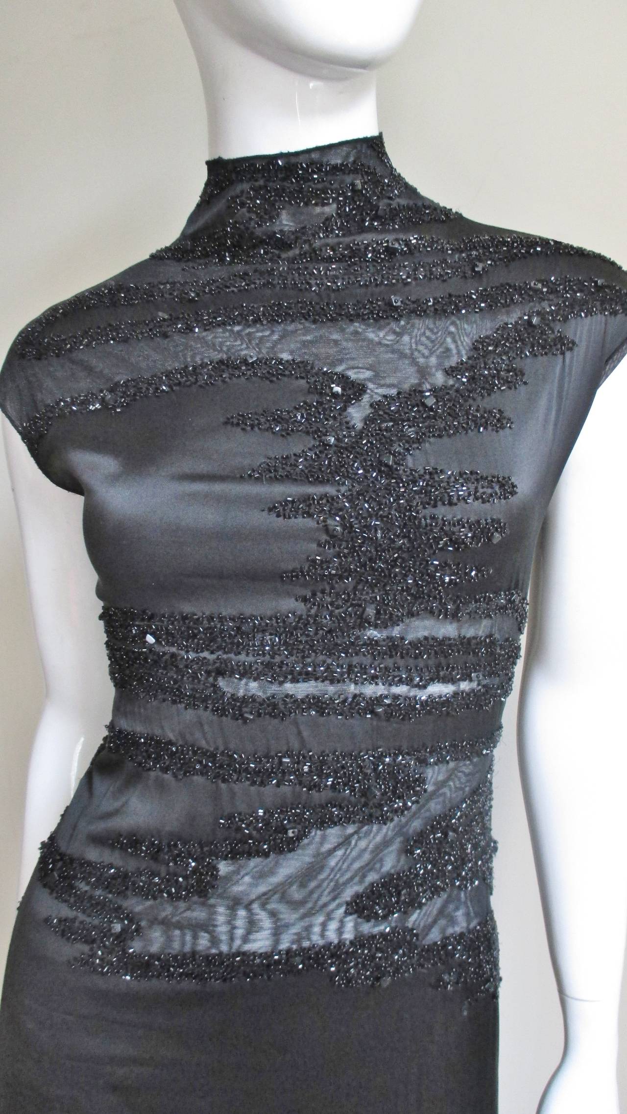 A stunning Krizia stretch silk dress with abstract shaped sheer netted areas, outlined with sparkling black glass beads, strategically placed on the front and more free form on the back, hip and hem. It has a stand up collar,  extended cap sleeves,