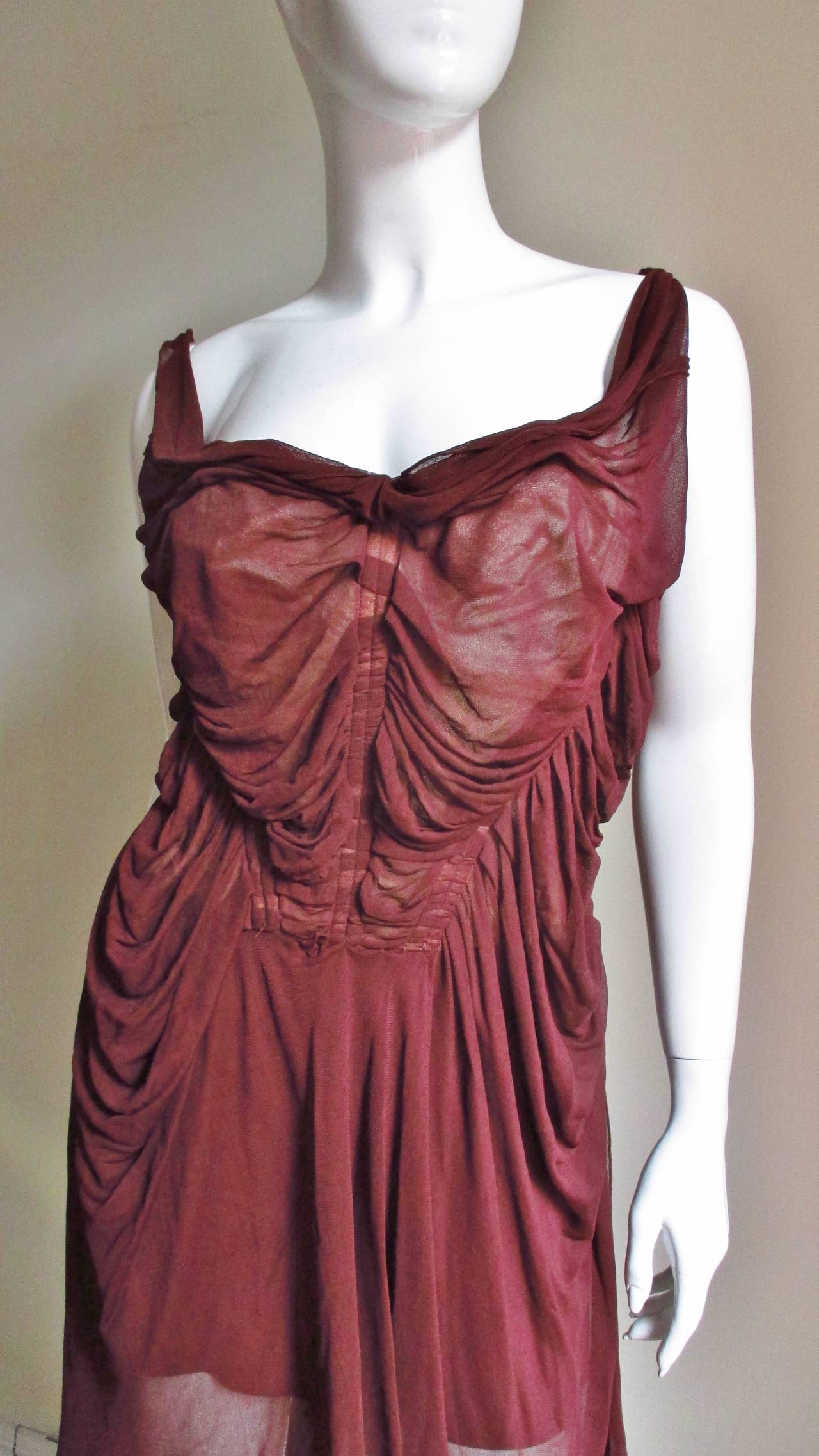 A delicate sheer maroon silk corset dress from Jean Paul Gaultier.  It has a  draped ruched bodice with small straps and laces up at the back.  There is draping along the sides at the waist and the skirt has seams at different angles which fall into