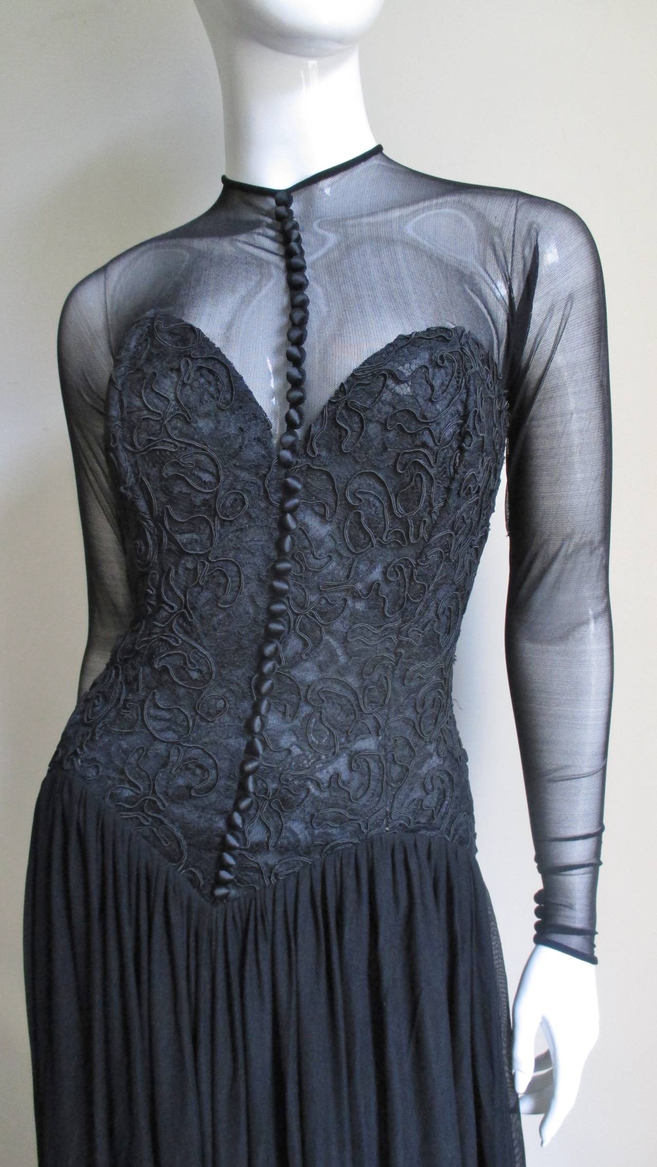 A fabulous black dress from Vicky Tiel.  It has a fitted boned bustier bodice with a dropped V waist in an intricate corded lace pattern with silk buttons and loops onto which a full silk mesh skirt is gathered.  It is striking with sheer sleeves,