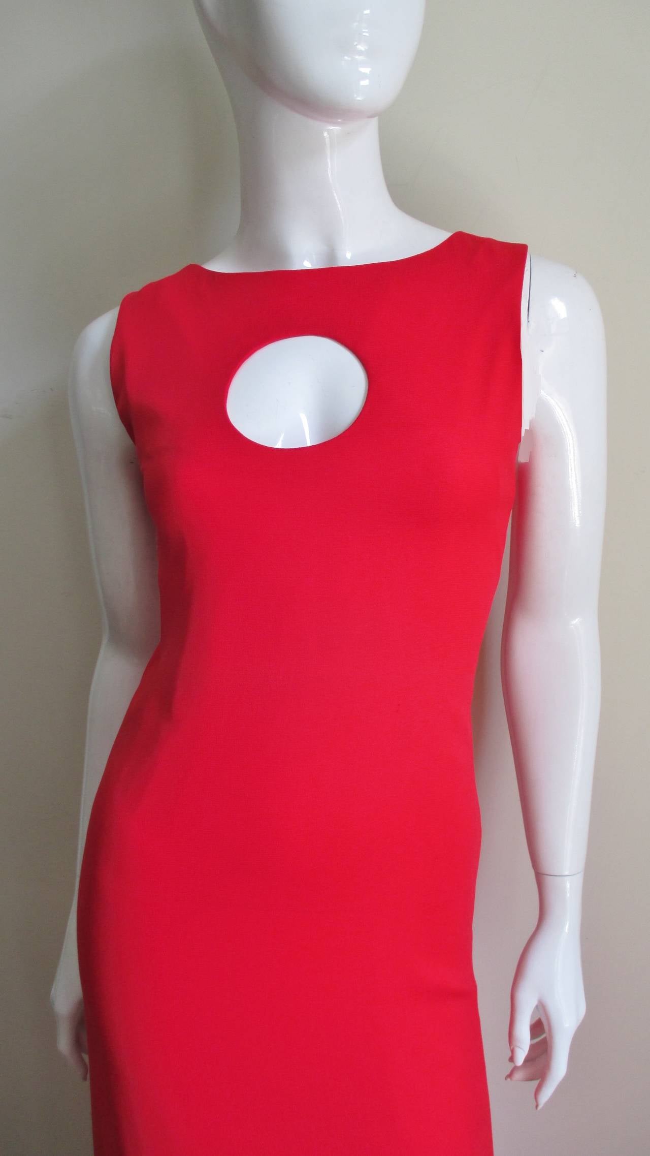 A vintage Pierre Cardin bright red crepe full length dress with a circle cutout at the chest. The neckline is a crew neck from the front with the shoulders forming straps which attach to a straight cut back. The dress skims the body to the waist and