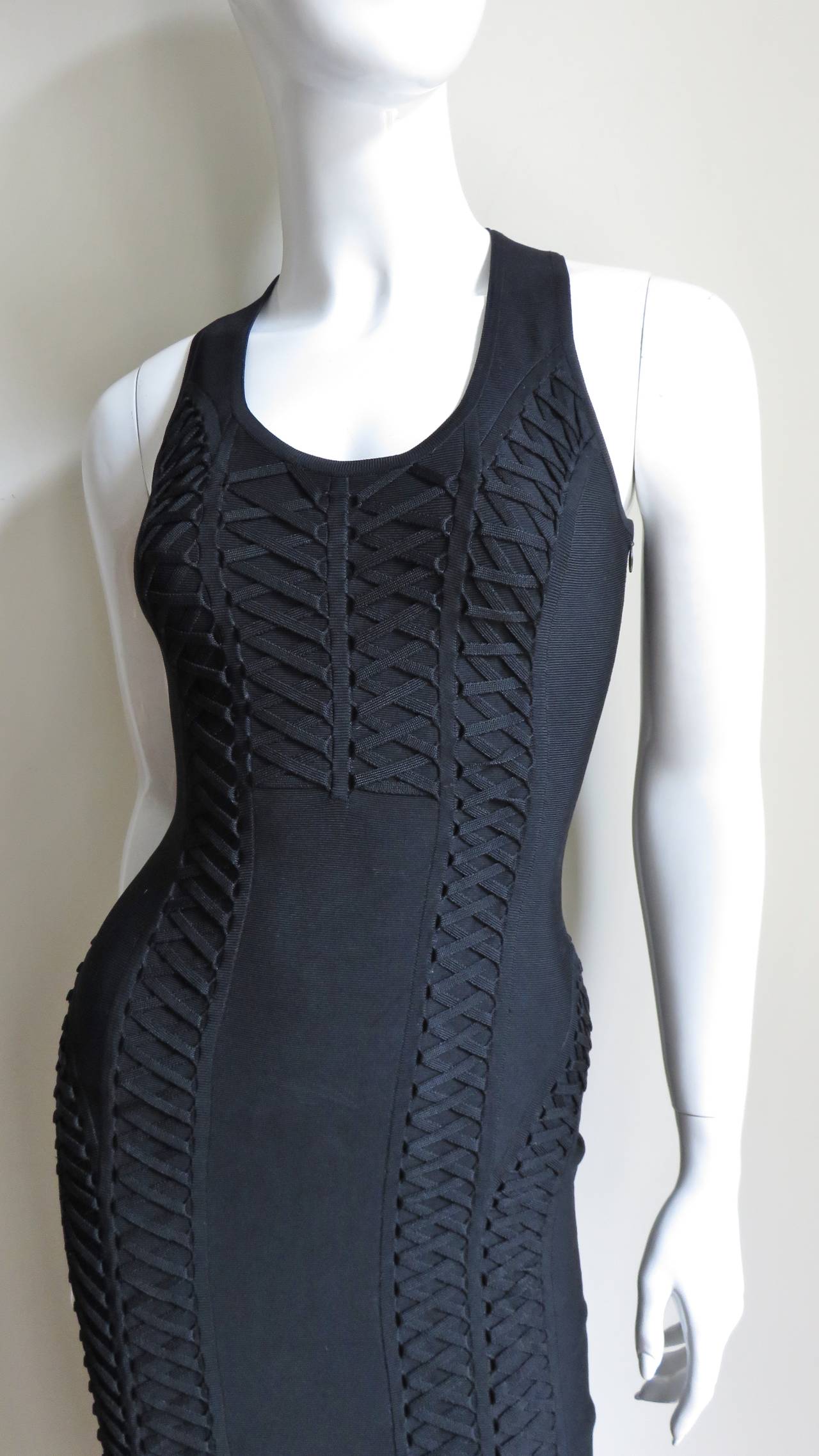 An incredible black stretch bandage fitted black dress from Christian Dior.  It is sleeveless with a scoop neckline.   The compression bandage material (like Herve Leger's designs) has vertical rows of fixed lacing detail highlighting shape in the