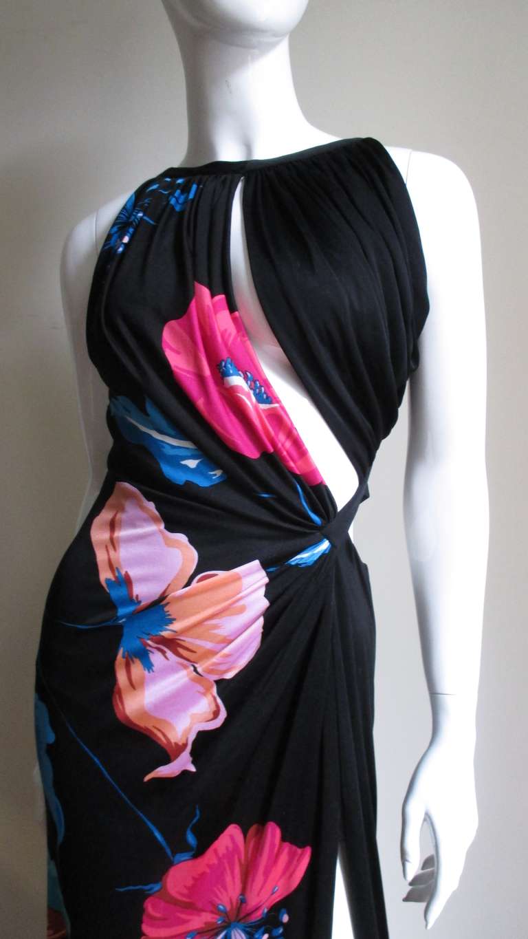 This is an amazing soft slinky silk jersey dress from Gianni Versace Couture a black background with large bright flowers in turquoise and shades of pink. The dress is flatteringly draped on one side and has a curved draped cutout starting from the