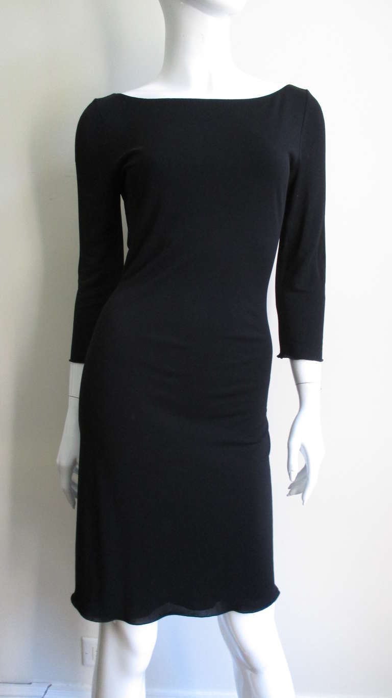 An amazing modern twist on a little black dress in a synthetic jersey from Jean Paul Gaultier. Simple and fitted from the front with a bateau neckline and 3/4 length sleeves.  But from the back dramatically low cut with an intricate criss crossing