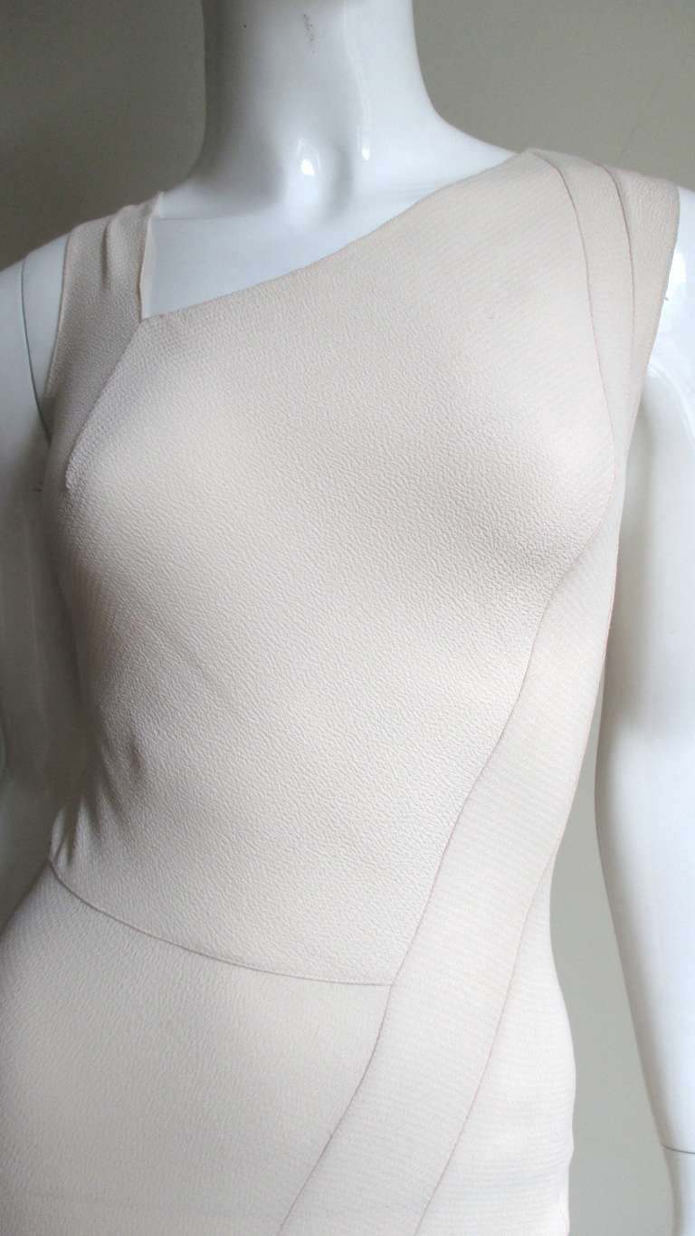 A Christian Dior gown, in the palest shade of blush silk, reminiscent of the 1930's.  A long fitted sleeveless silhouette with asymmetrical neckline and seaming.  Tucking/seaming start at one shoulder angling down to the center front thighs ending