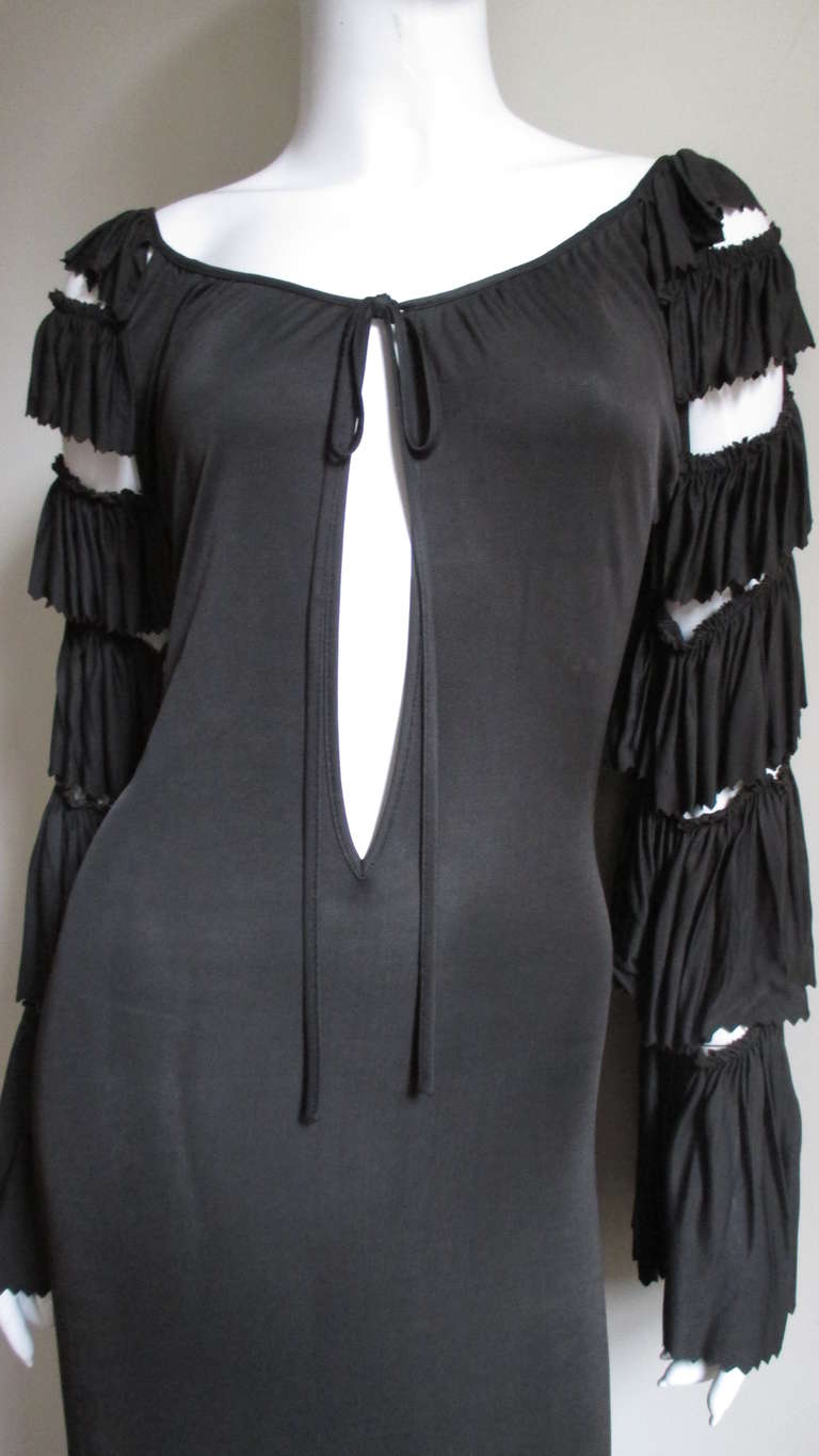 A great slinky dress in a charcoal synthetic jersey from Jean Paul Gaultier. It has a wide scoop neckline with a long keyhole with ties. And those fabulous rumba style sleeves with rows of pinked edged ruffles which show skin in between.  The dress