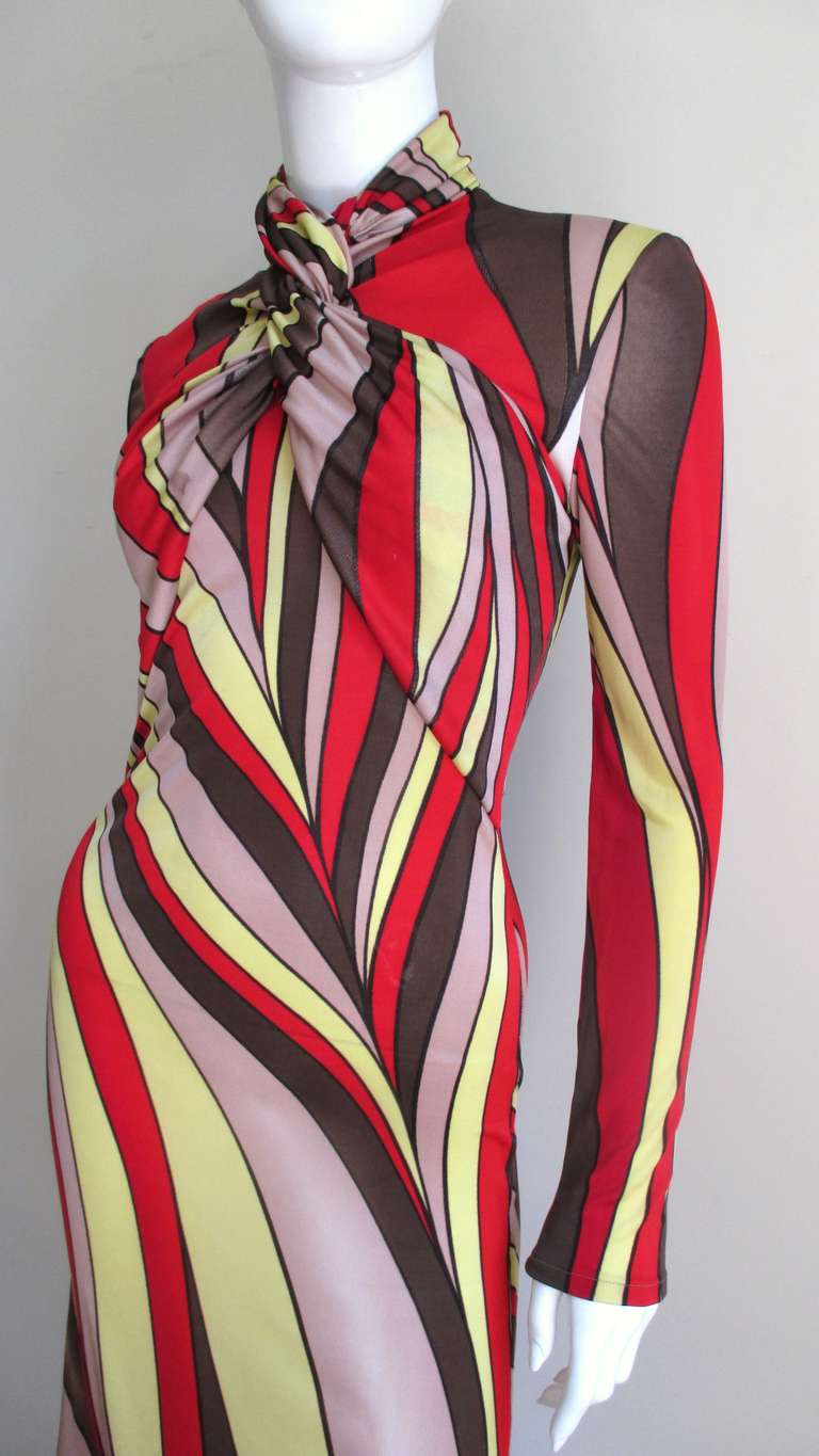 A fabulous silk knit dress from Gianni Versace Couture in a mod abstract pattern in brilliant shades of red, yellow, brown and rosy beige.  The fitted long sleeve dress has a fabulous wrapped neckline that crosses in the front across the bust into