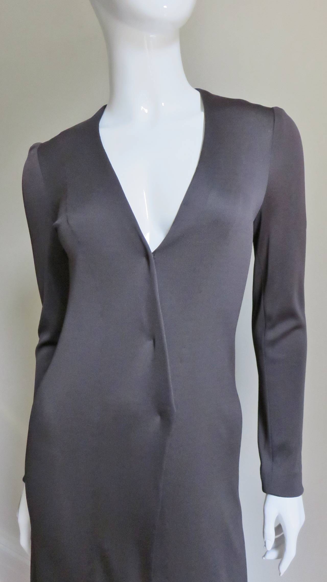An excellent example of the classic elegance of Halston.  Made of charcoal grey jersey it is a long sleeve shirtwaist style maxi dress with a matching tie belt.  It  has an adjustable plunging neckline and closes with snaps down the front of the