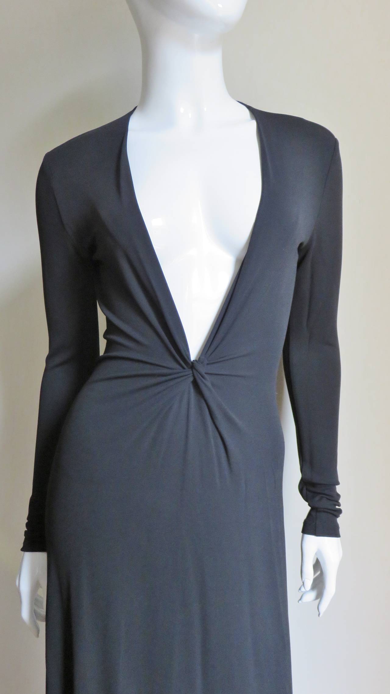 A beautiful rich black silk jersey dress from Celine.  It has a deep plunging neckline, fitted long sleeves and gathering on each side that meet at a knot at the center front waist.  The dress front is cut in one piece with the skirt which flares