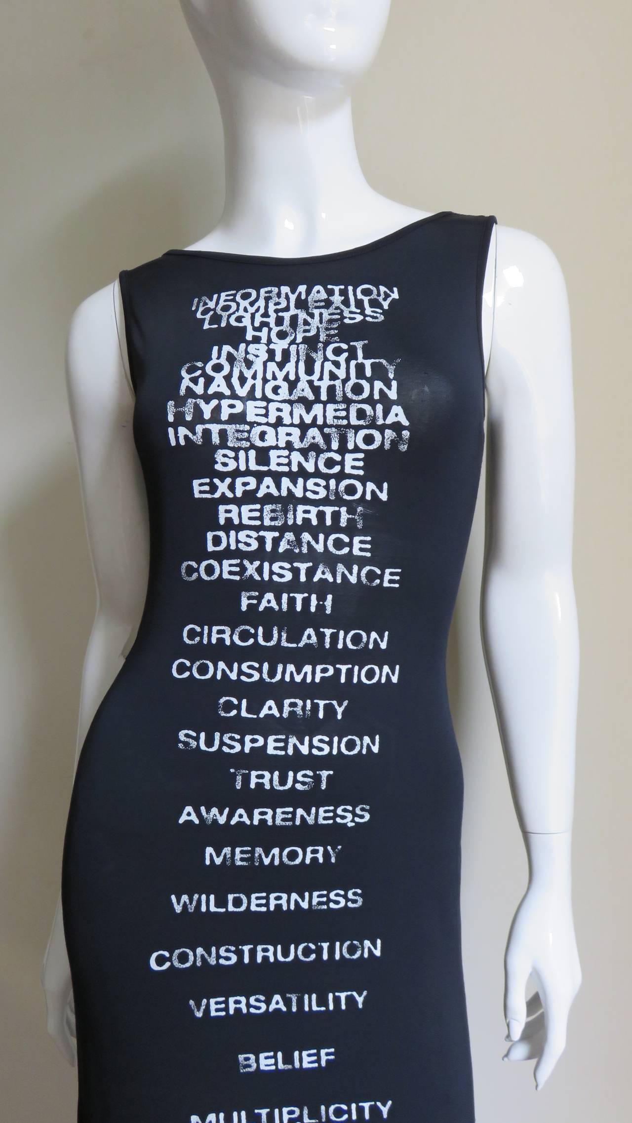A great jersey maxi dress from Moschino.  It is a sleeveless long column of black jersey with a list of white semi distressed screen printed words down the length of the front.  It has a side slit, slips on over the head and is unlined.
Excellent
