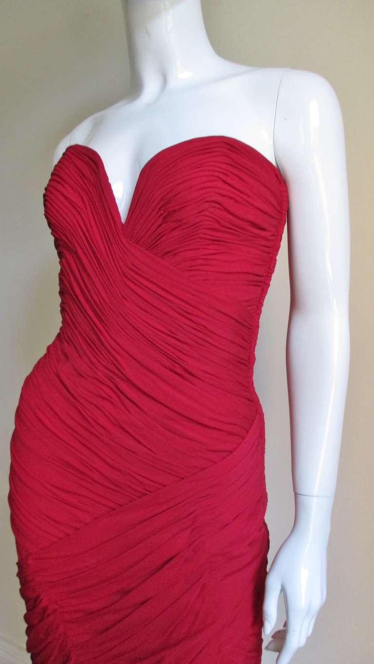 A fabulous strapless dress in a ruby red silk jersey from Vicky Tiel.  The dress is comprised of patterns of intricate ruching in different directions.  It has a strapless sweetheart cut neckline, boned bodice and is fitted through to the hem.  A