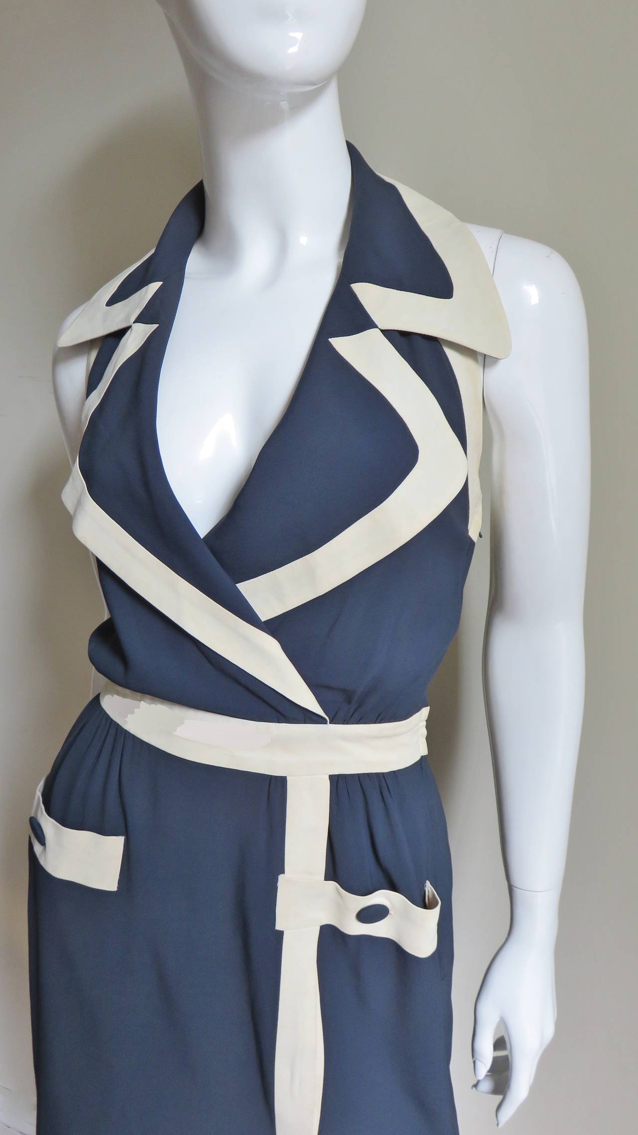 A great navy and off white halter dress from Moschino Couture. It has a wrap effect with large rounded notch collar, banded waist and faux pockets with buttons all are bordered in an inch of off white as is the hem and front wrap.  It is fully lined