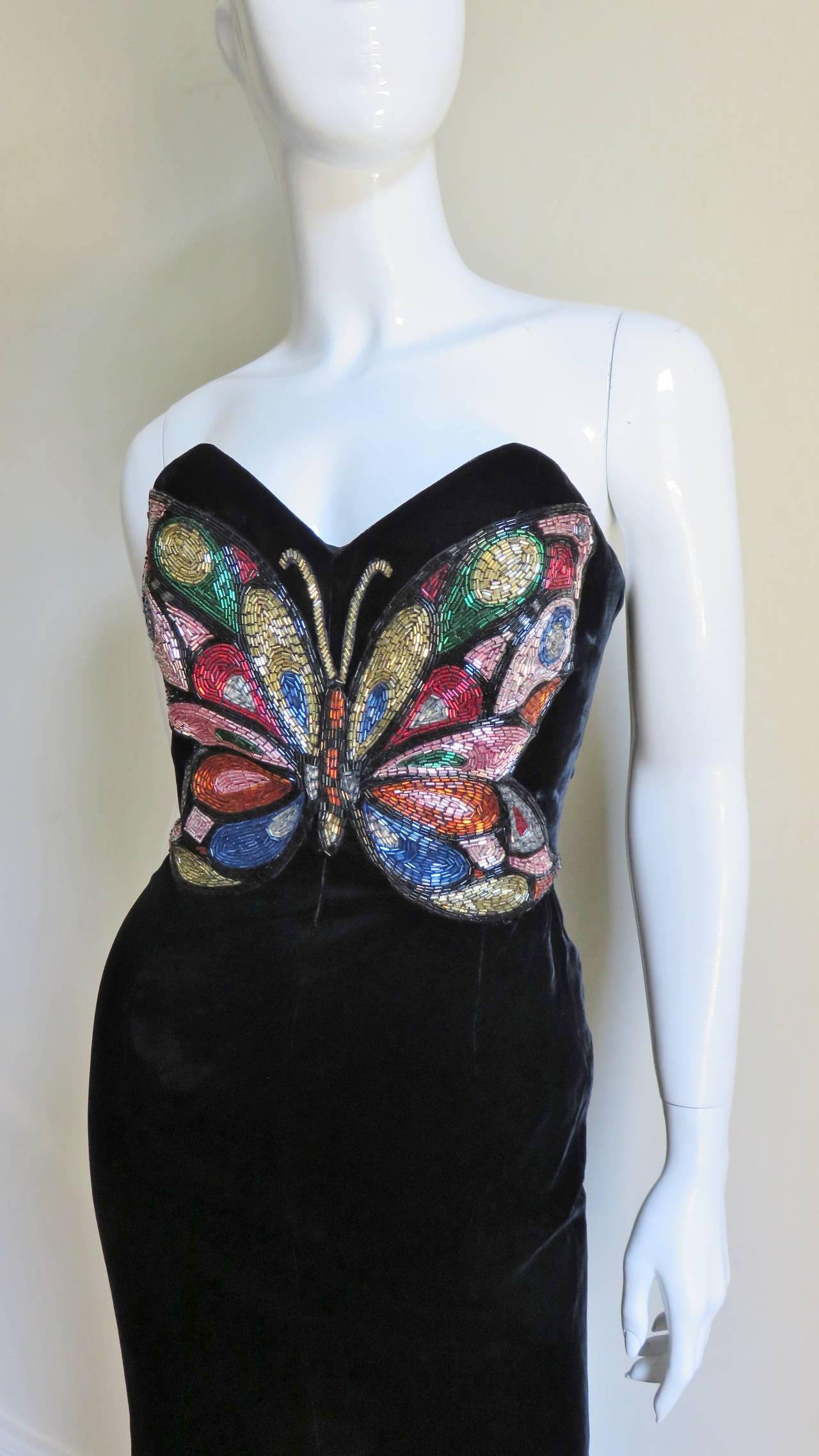 An incredible rich black silk velvet bustier dress from Oscar de la Renta with a fabulous, colorful, intricately glass beaded butterfly on the front bodice.  It is strapless, fitted through the waist to the thighs then flares in a mermaid style to