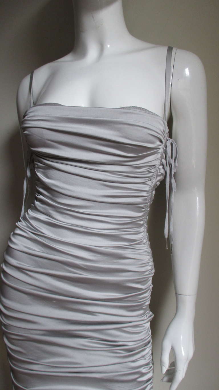 Fabulous silver silk bodycon dress from Dolce and Gabbana.  Fitted and ruched through the body and completely adjustable with a set of lacing along each side.  It has an attached adjustable matching padded bra that peeks out of the top of the dress