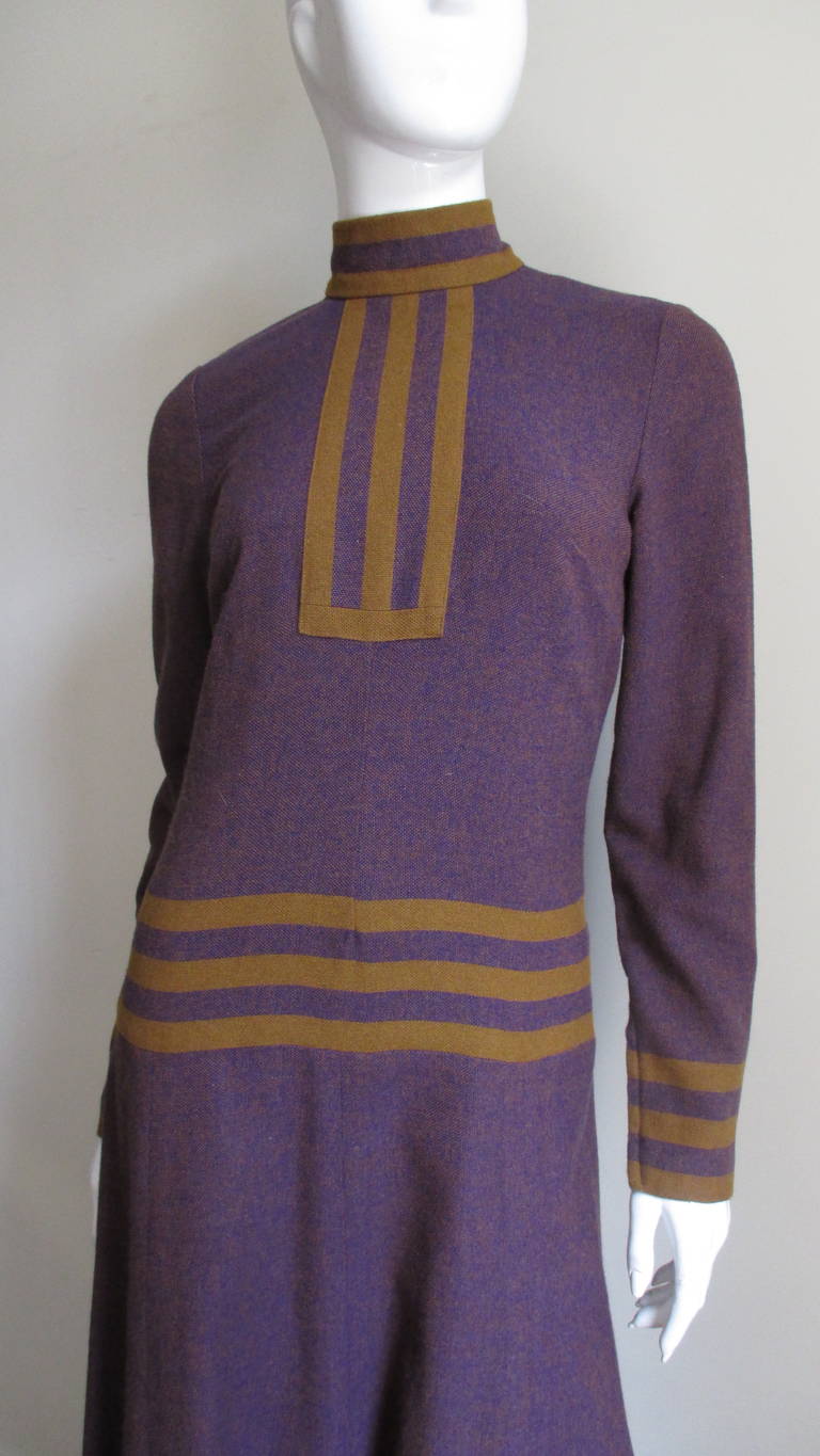 A fabulous purple and mustard wool maxi dress by Jean Varon.  It has a standup collar, long sleeves and a long flaring skirt.  There is a striped mustard and purple panel at the center front bodice and another around the upper hips, neckline, sleeve