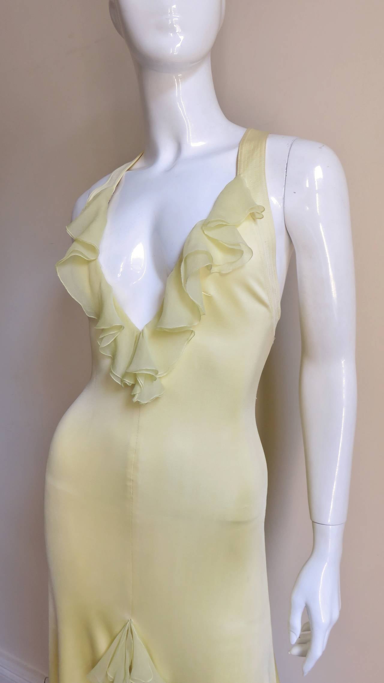 A gorgeous stretch silk dress in a lovely lemon shade from Versace.  It has a deep plunging chiffon ruffle neckline, is fitted through the body and has a center front chiffon ruffle slit at the hem.  The multi top stitched shoulder straps attach to