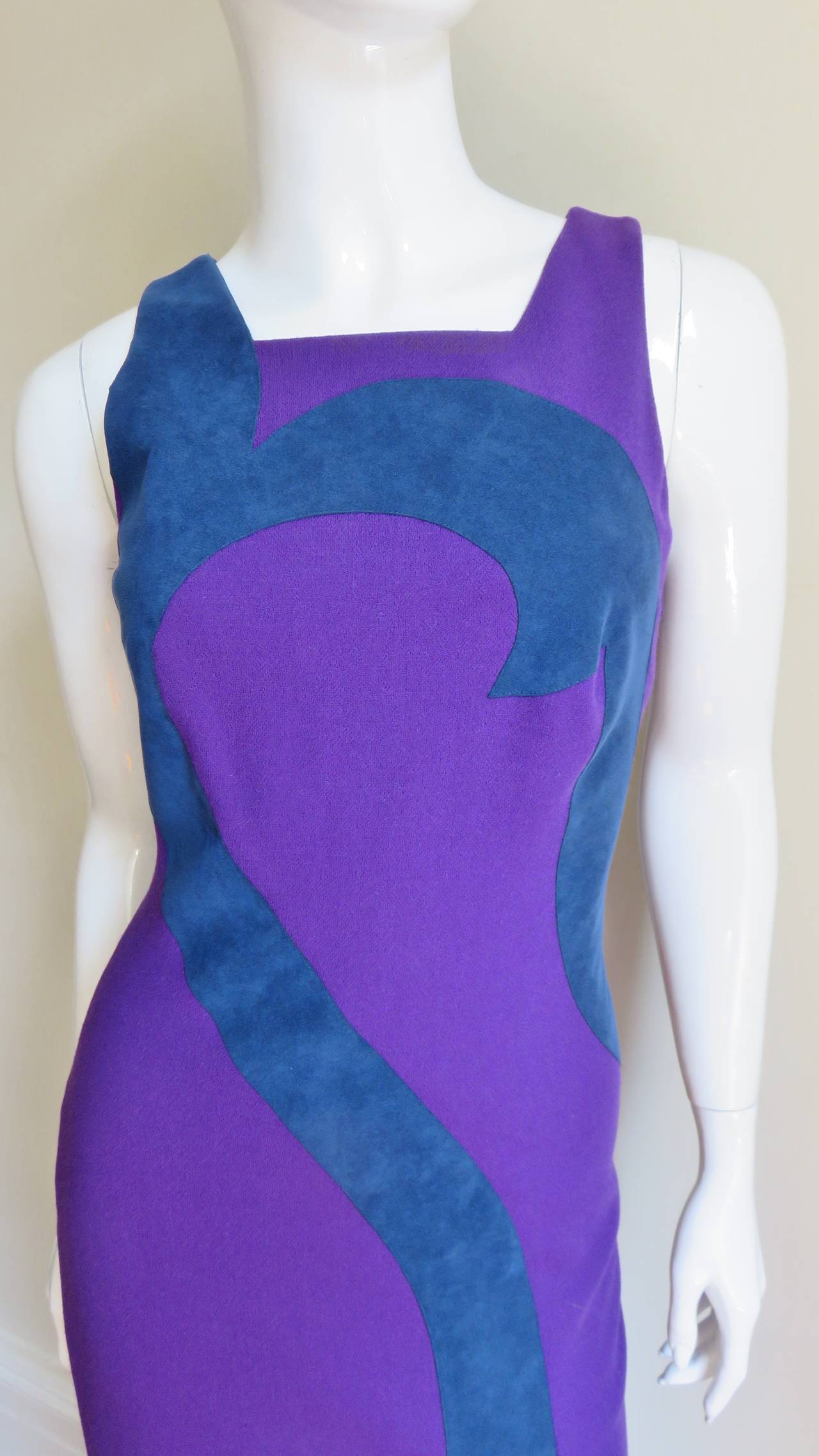 A great dress from Versace in a rich purple wool with a blue ultrasuede abstract desgin inserted across the bust curving down the length of the dress from and back.  It is sleeveless body conscious design with a square neckline and front slit along
