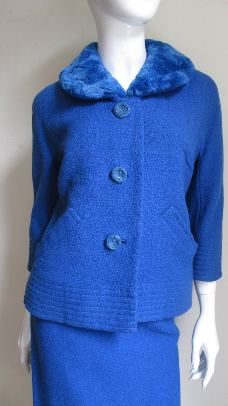 A gorgeous royal blue wool 2 piece skirt suit with a dyed to match sheared  mink collar.  The boxy cut jacket is cut in one piece with the sleeves, has underarm gussets, 2 pockets, large matching buttons with bound buttonholes and 3/4 length