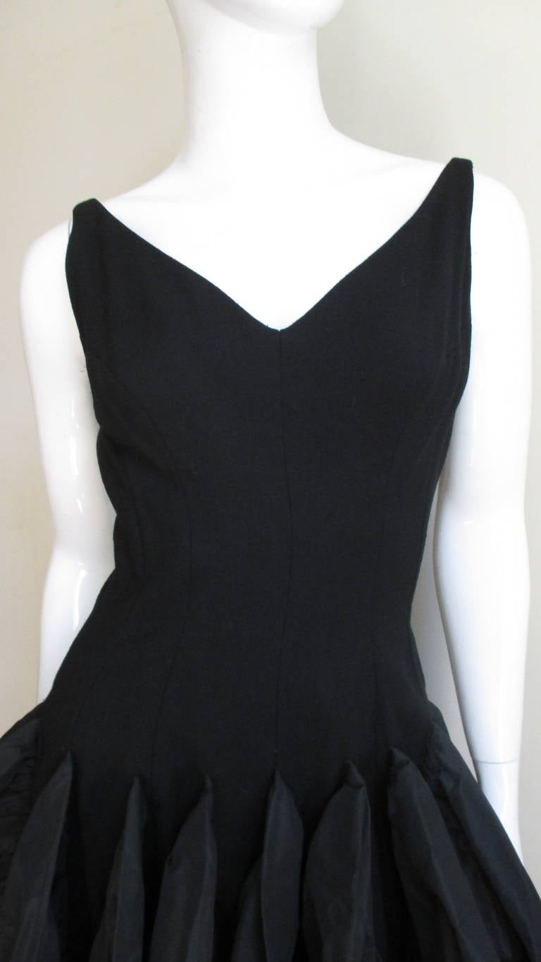 A fabulous dress from Betty Carol in light weight black wool and silk taffeta.  It  has a V neck front and deeper V back with fabulous princess seaming creating a fitted silhouette through to the lower waist.  From there it flares into a rounded