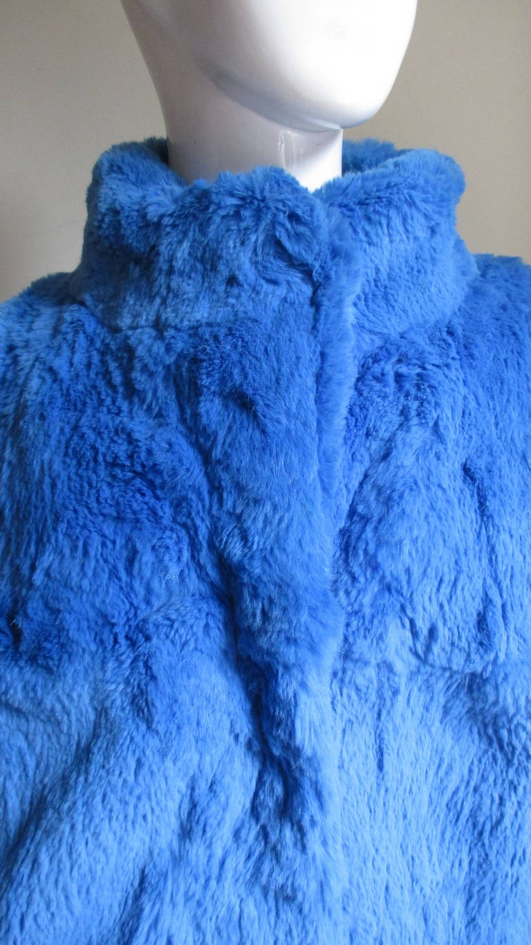 A beautiful brilliant blue oversized 1980's rabbit fur jacket in an oversized.  It has a standup collar, dolman sleeves with cuffs, matching blue fur hooks up the front and side seam pockets.  The cuffs and hem are lightly elasticized for comfort