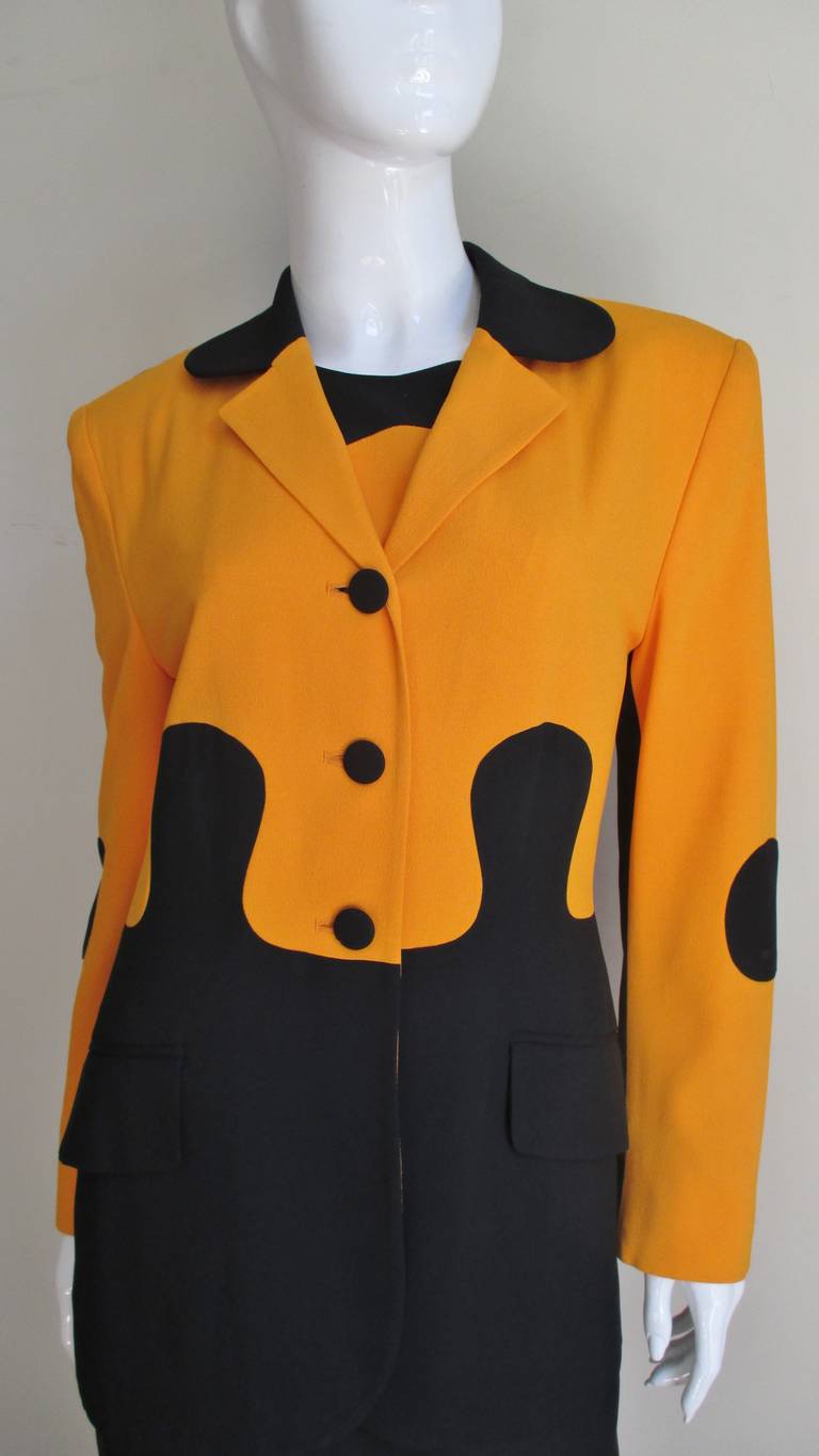 Fabulous set from Moschino in gold and black fabric sewn together in a puzzle pieces pattern.  The dress is a simple sleeveless shift with the patterned reversed on the back.  The long sleeved jacket has lapels, flap front pockets and self button