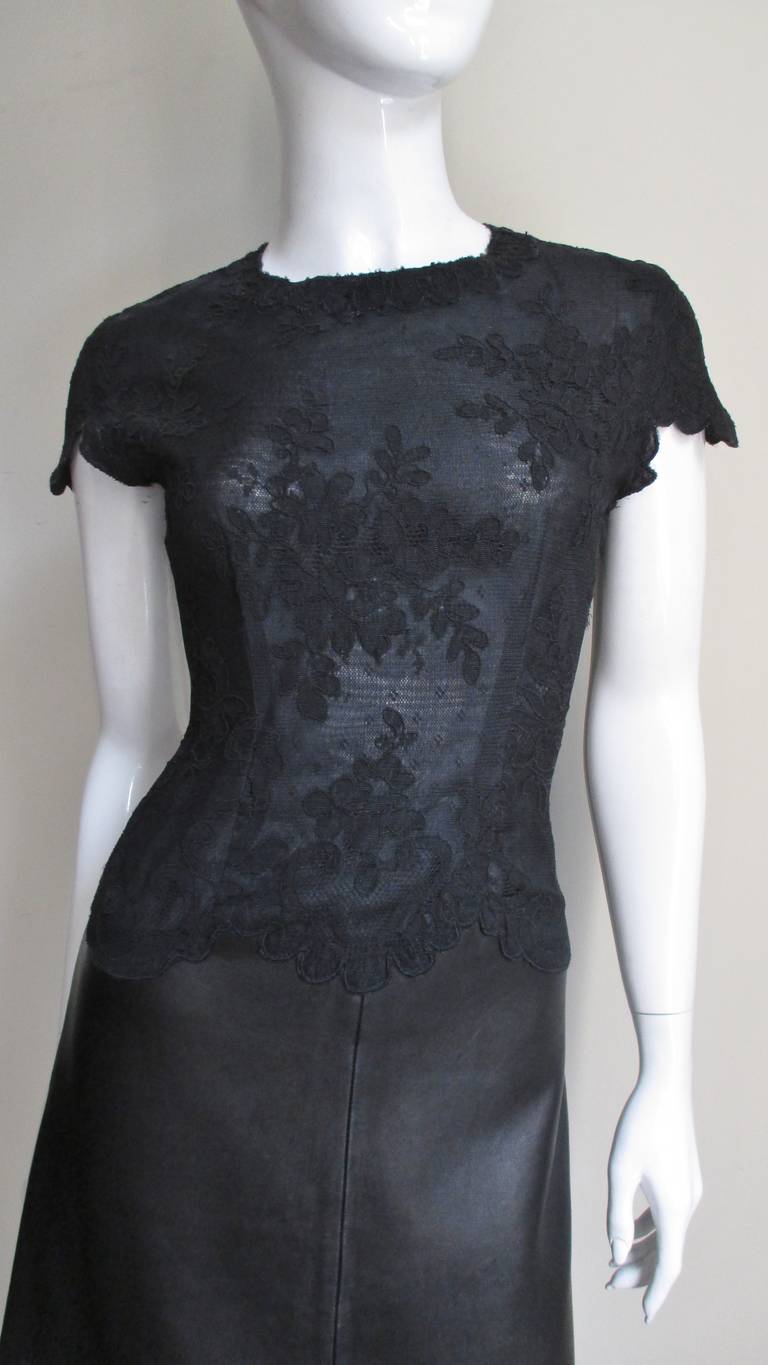 A fabulous little black leather and lace dress by Gianni Versace.  It has flowered lace on top with finishes following the edges of the lace pattern along the hem, cap sleeves and waist.  It is fitted through the bodice and has a slight A line
