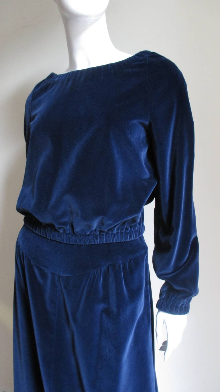 A fabulous 2 piece velvet set from Courreges in deep sapphire blue.  The maxi skirt is gathered onto a curved yoke front and back. The bateau neck blouson style top has stretch at raglan sleeve wrists, waist and neck which can be pulled to reveal a