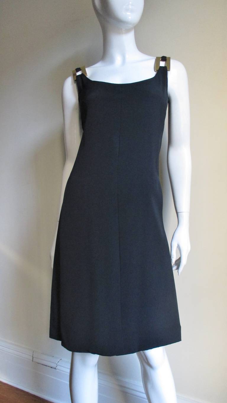A great little black silk dress from famed American designer Donald Brooks.  I has a scoop neckline front and back and straps adorned with 2 gold metal rectangles on the front and back.  It skims the body flaring towards the hem, is fully backed in