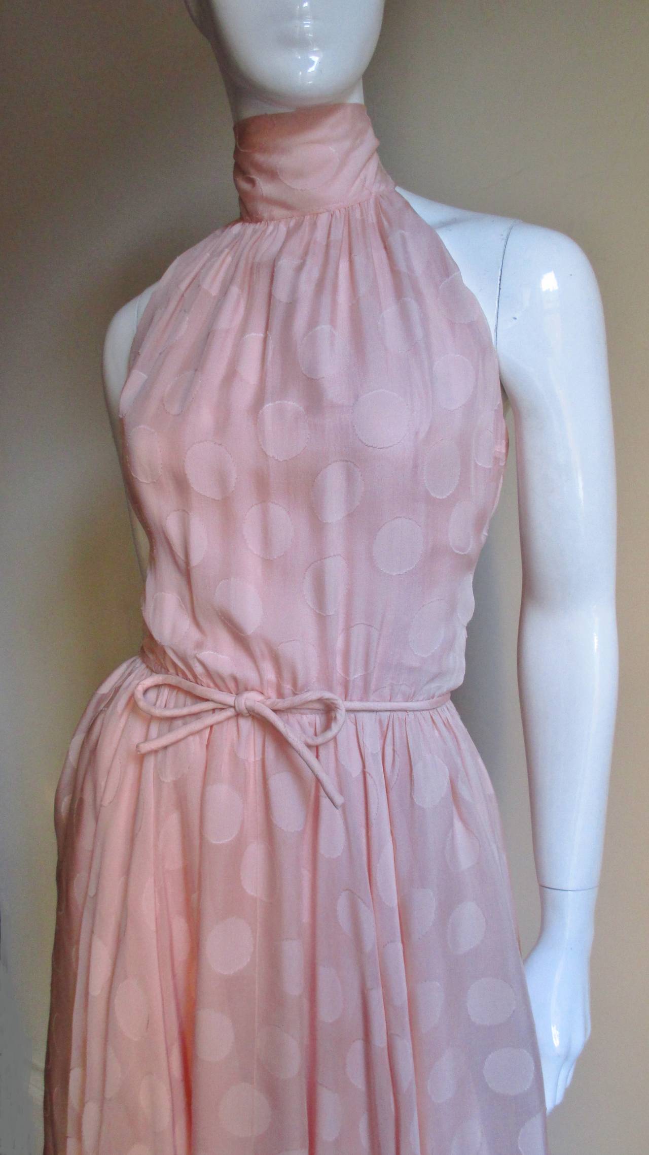 A stunning & feminine pink 1950's numbered dress from Christian Dior.  It is a delicate pink silk damask with circles on a semi sheer  background.  The dress has a halter neck which ties and drapes like a scarf in the back.  The bodice has boning at
