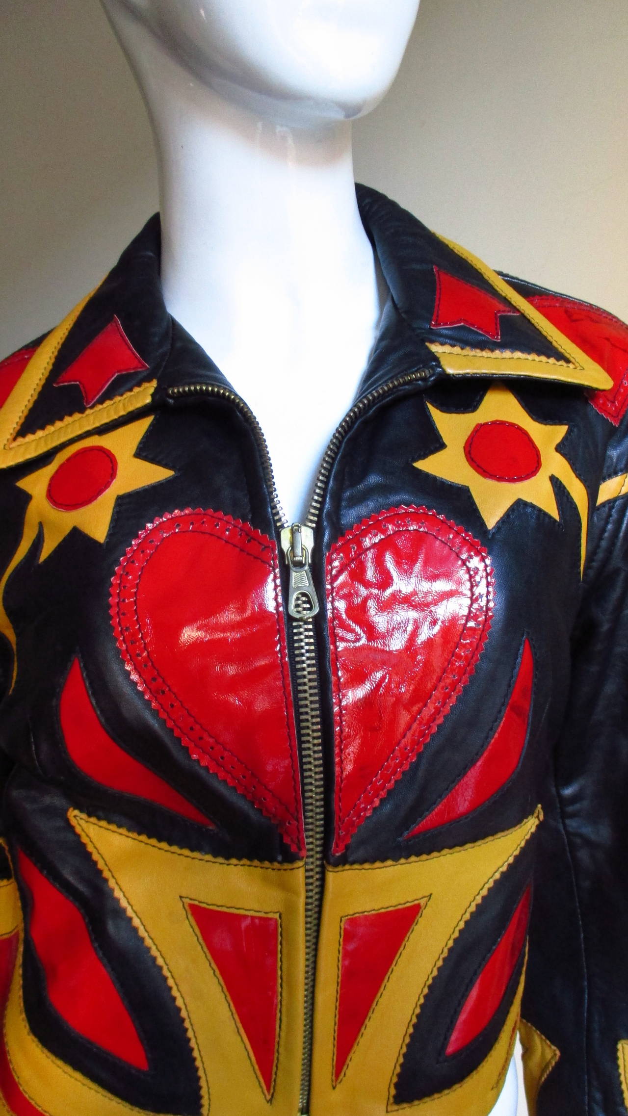 A stunning super soft, supple leather jacket from Moschino in a great combination of gold leather and red patent leather on a black leather background.  Intricate cutouts with insets and appliques of flowers, leaves, stars, circles and abstract