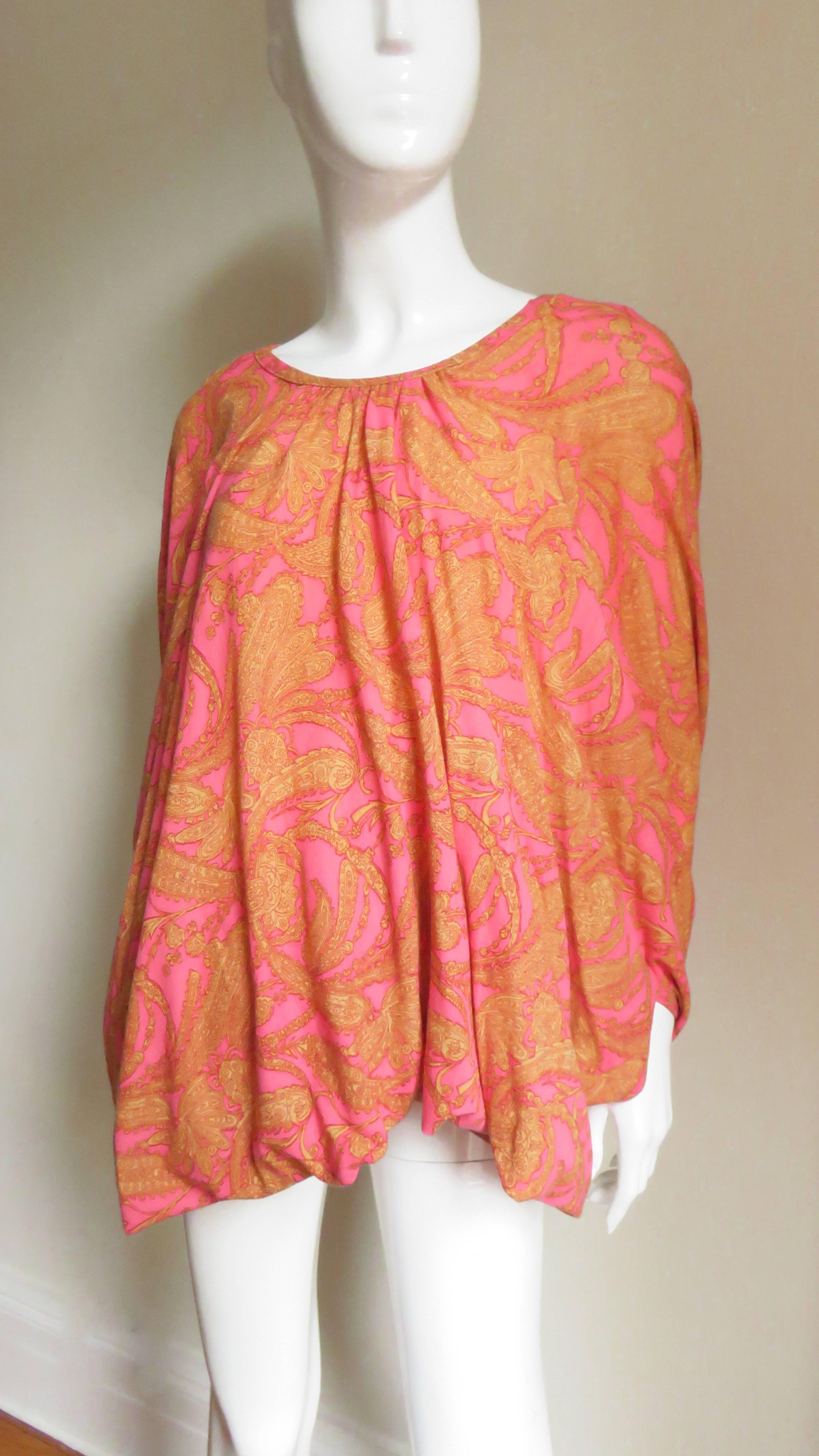 A fabulous fine light weight jersey top in a pink and yellow paisley pattern from Comme des Garcons, CDG.  The top is comprised of draping from the crew neckline to the band at the hem.  There are 2 side openings mid way on the sides for the arms. 