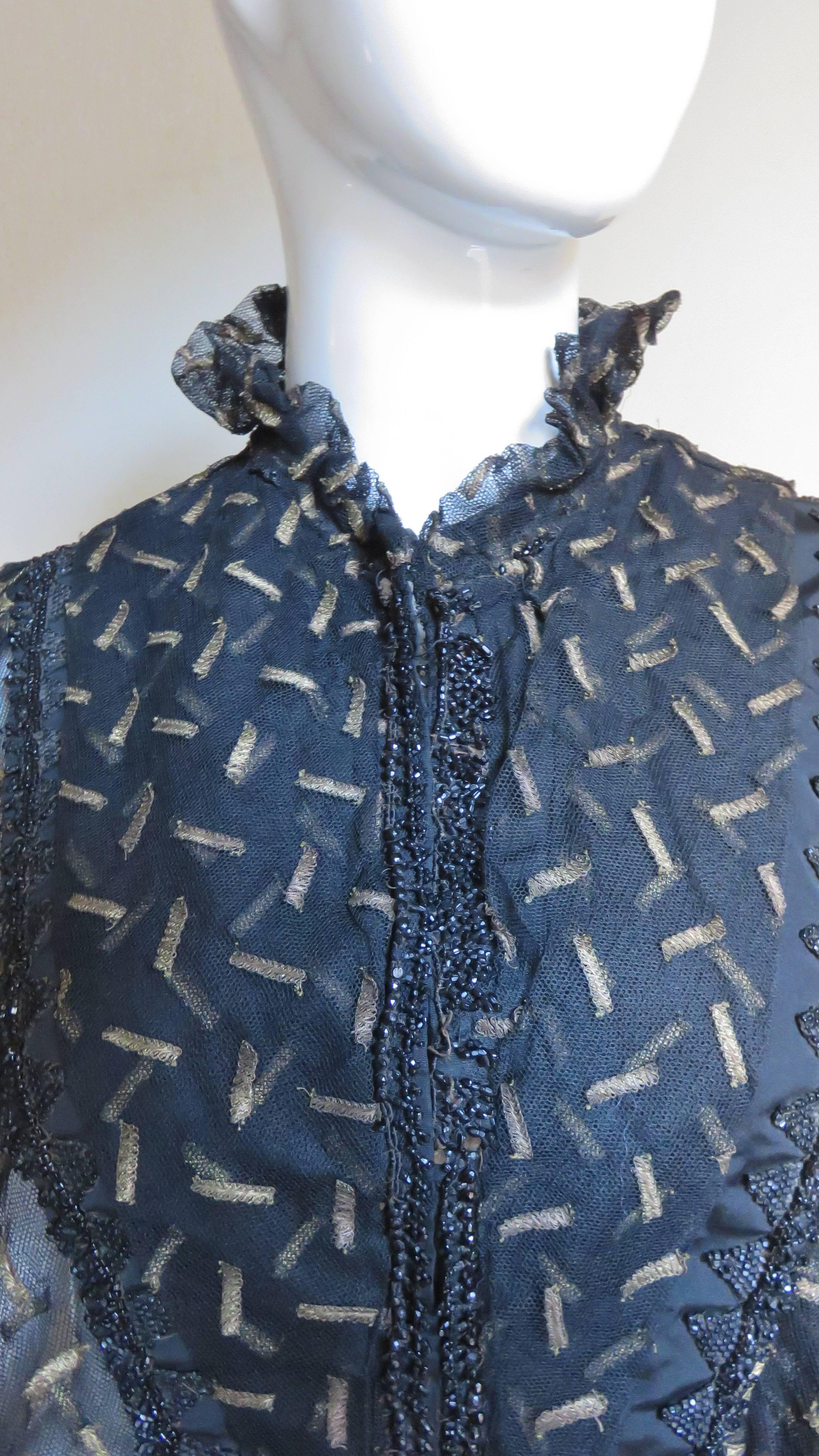 This is a stunning piece of fashion history.  It is a black heavy net cape or mantel from the 1890's. It has a ruffle collar, a black silk front/back under bib and beautiful pointed detail at the hem. The net is beautifully embroidered with fine