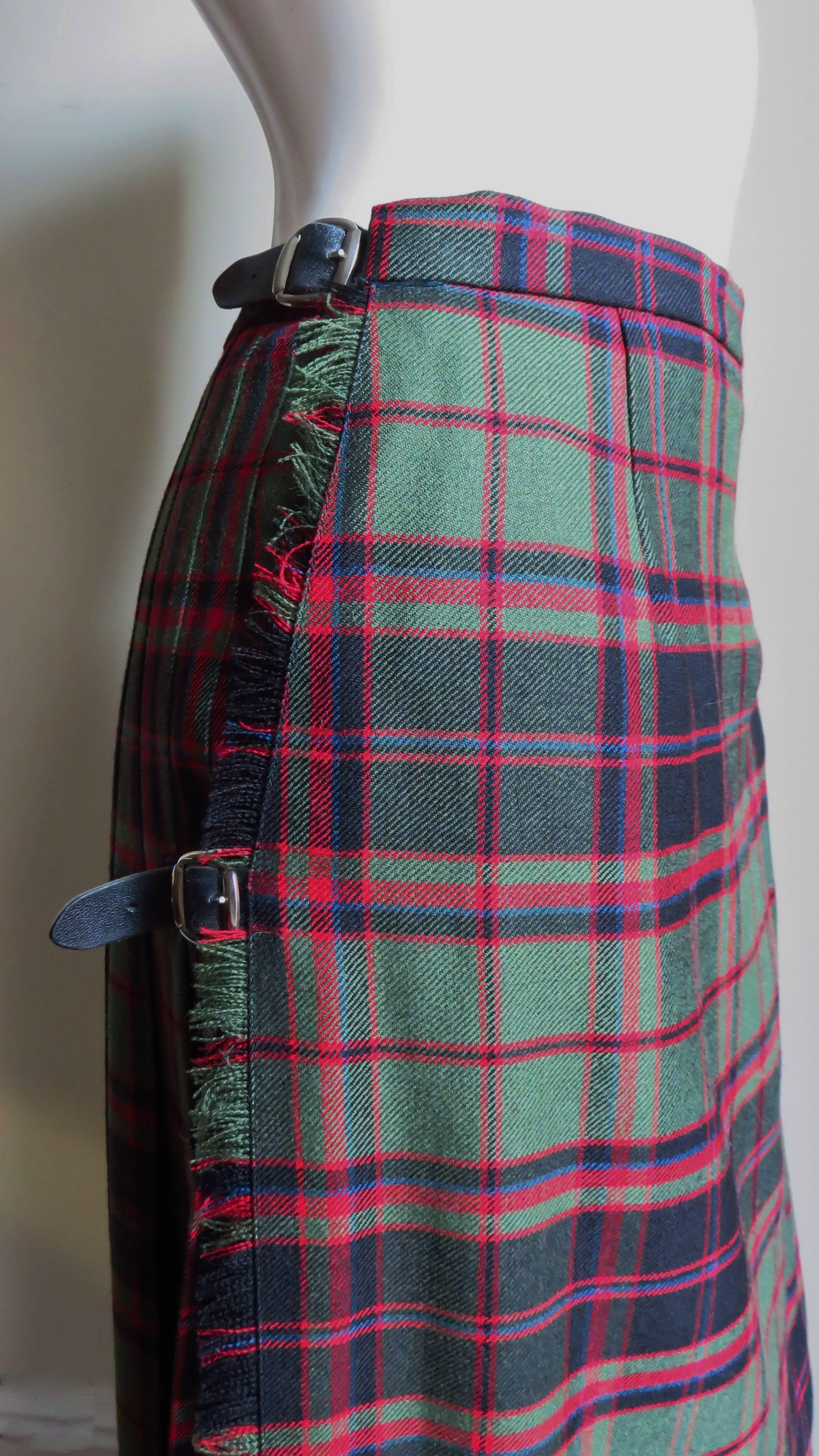 A fabulous plaid wool maxi kilt in festive holiday colors of red and green with  black.  It is a traditional kilt style with a fitted waistband including adjustable side leather belts, a wrap flat front with a side pin and a pleated back.  It is