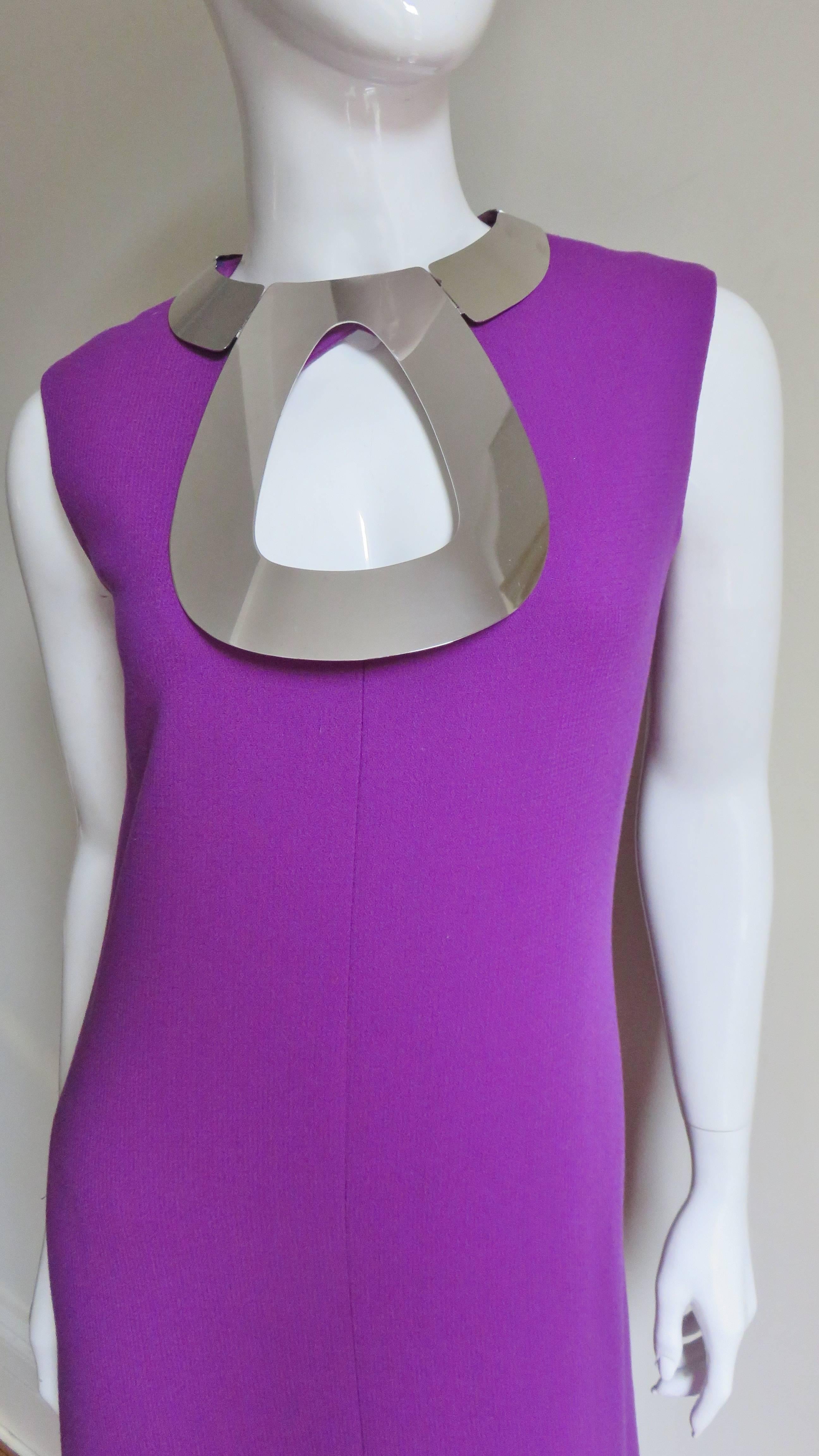 Am amazing dress purple wool dress from Pierre Cardin.  It is sleeveless, slightly fitted, midi length with a center front slit.  It has a stunning silver metal hardware articulating collar around the neckline and a large tear drop shaped cutout on